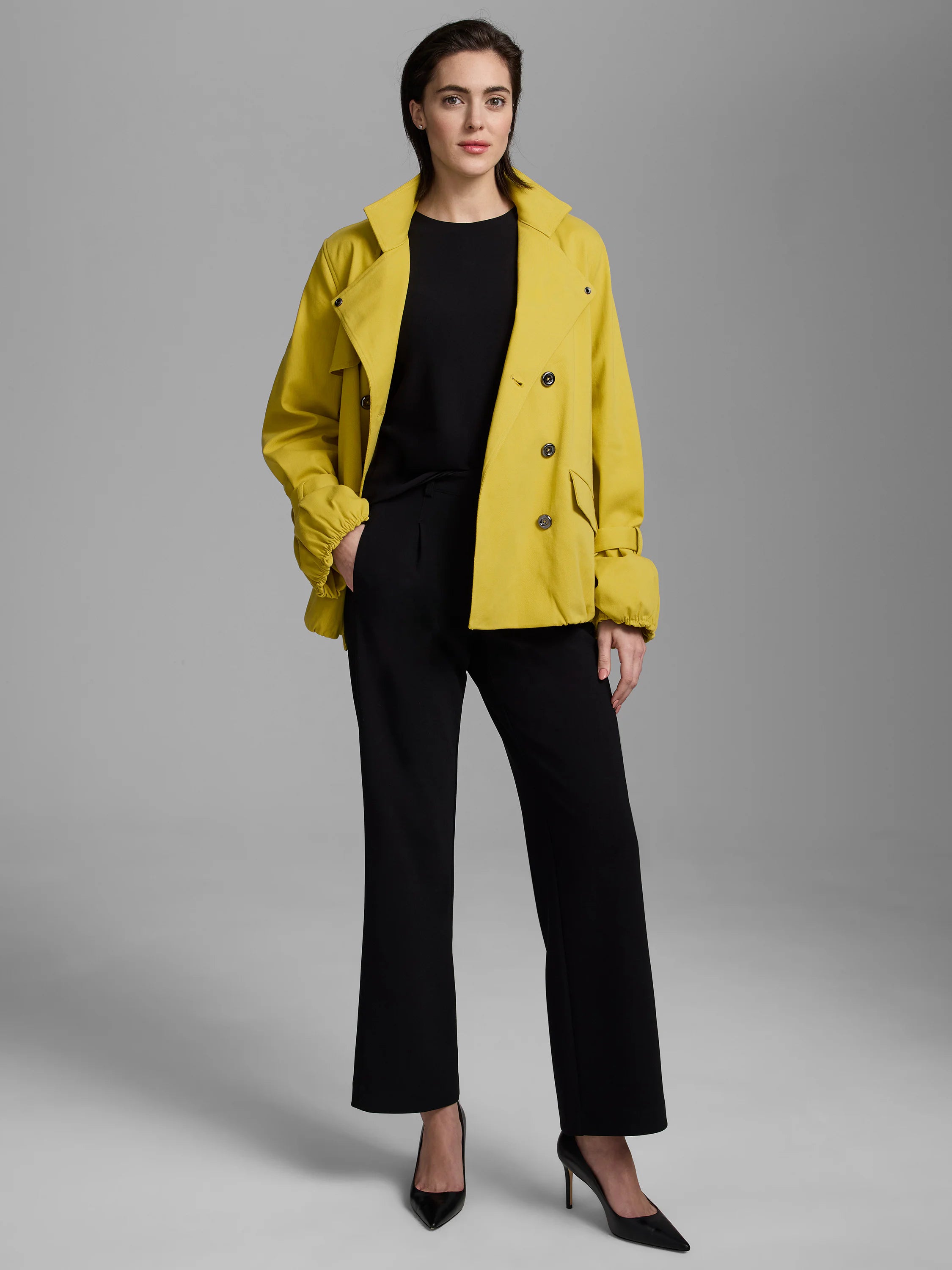 Black knit scuba high neck tank top worn by a model under a yellow jacket.