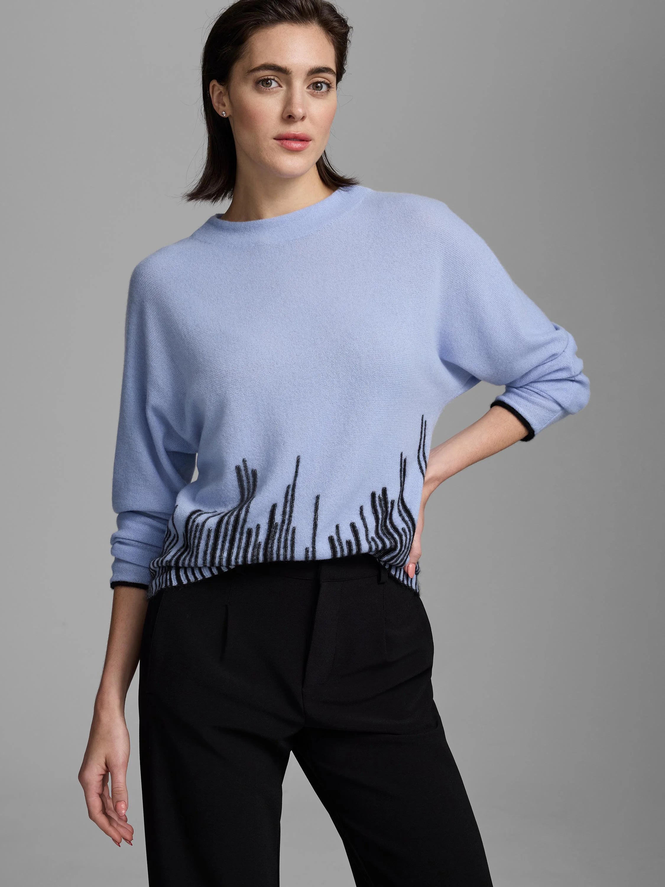 Light blue cashmere crew neck sweater with a black flame stitch pattern along the hem and cuffs.
