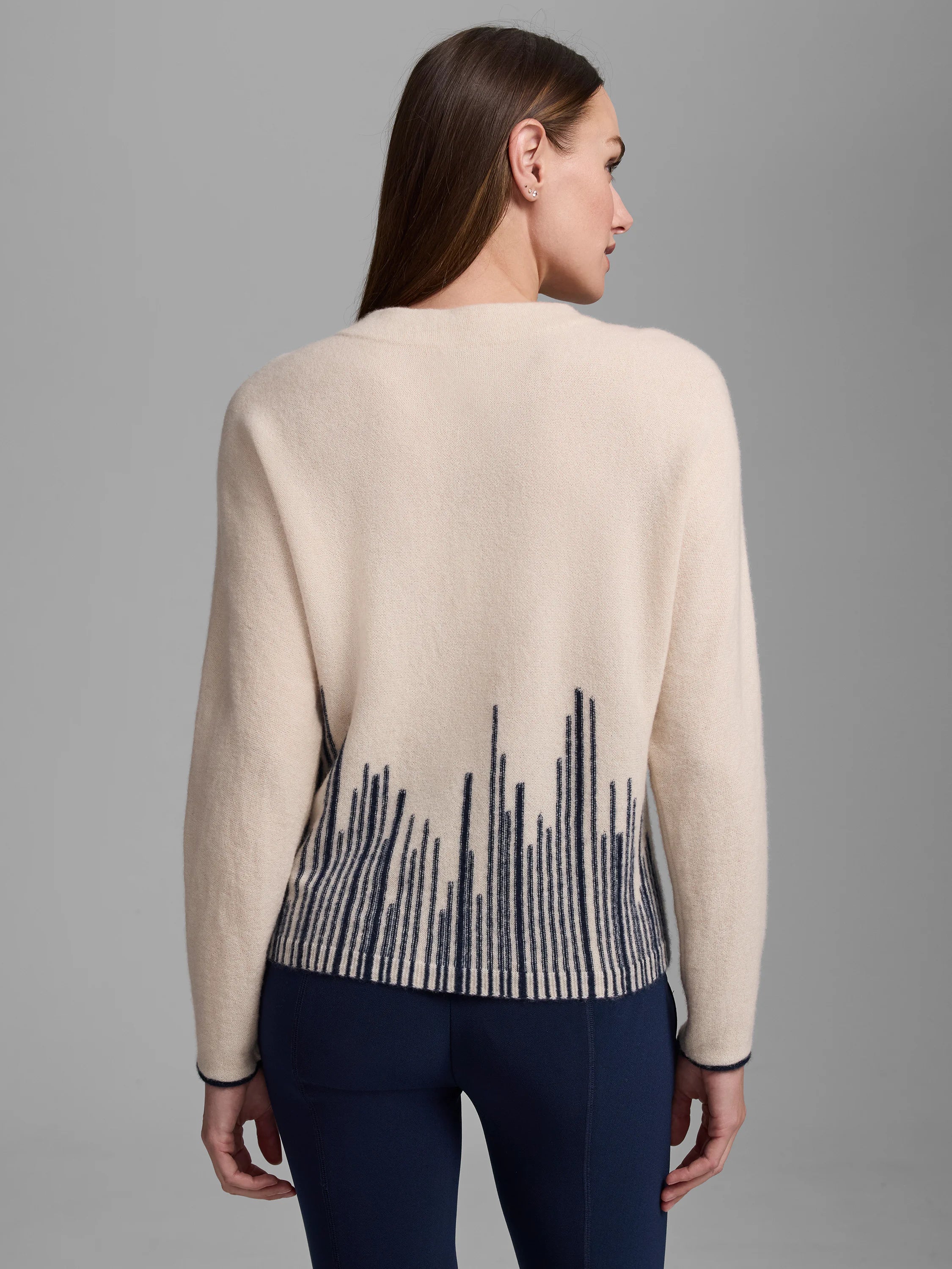 Cream cashmere sweater with navy flame stitch pattern on lower back. Navy trim on cuffs.