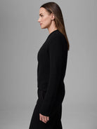 Black cashmere cardigan, soft texture, long sleeves, ribbed cuffs, worn as a closed top on a model.