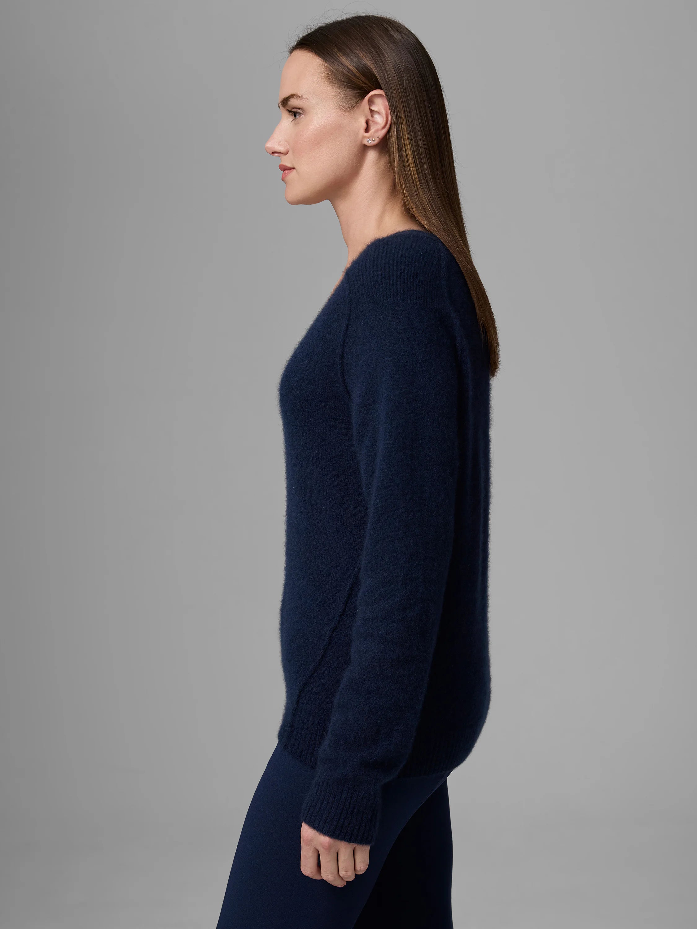 Dark navy V-neck cashmere sweater with soft, fuzzy texture and ribbed cuffs, modeled in profile.