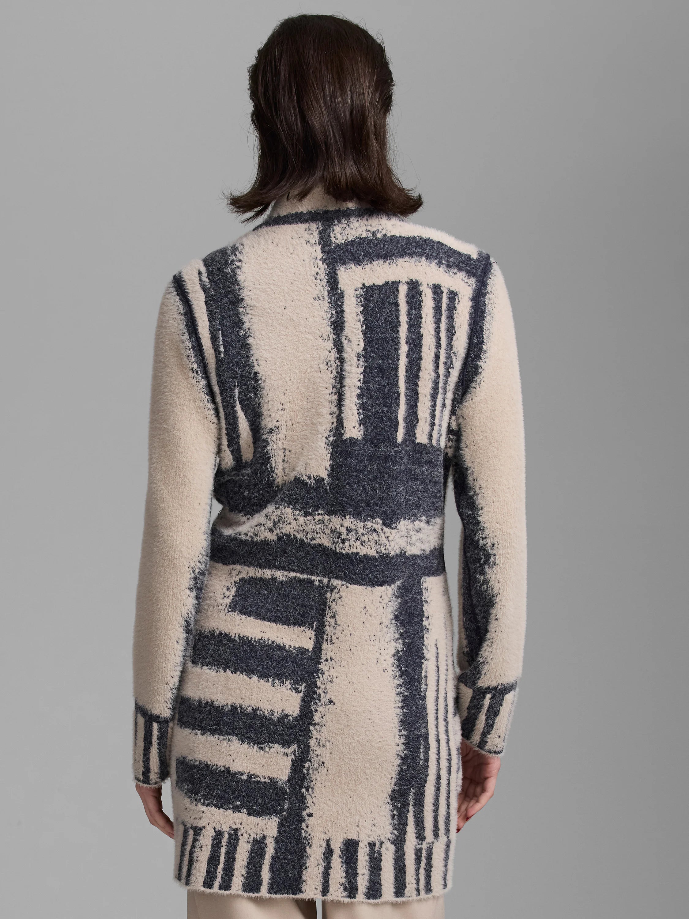 Back view: Fuzzy cream and charcoal textured jacket with an abstract stripe & block pattern. Appears mid-thigh length.