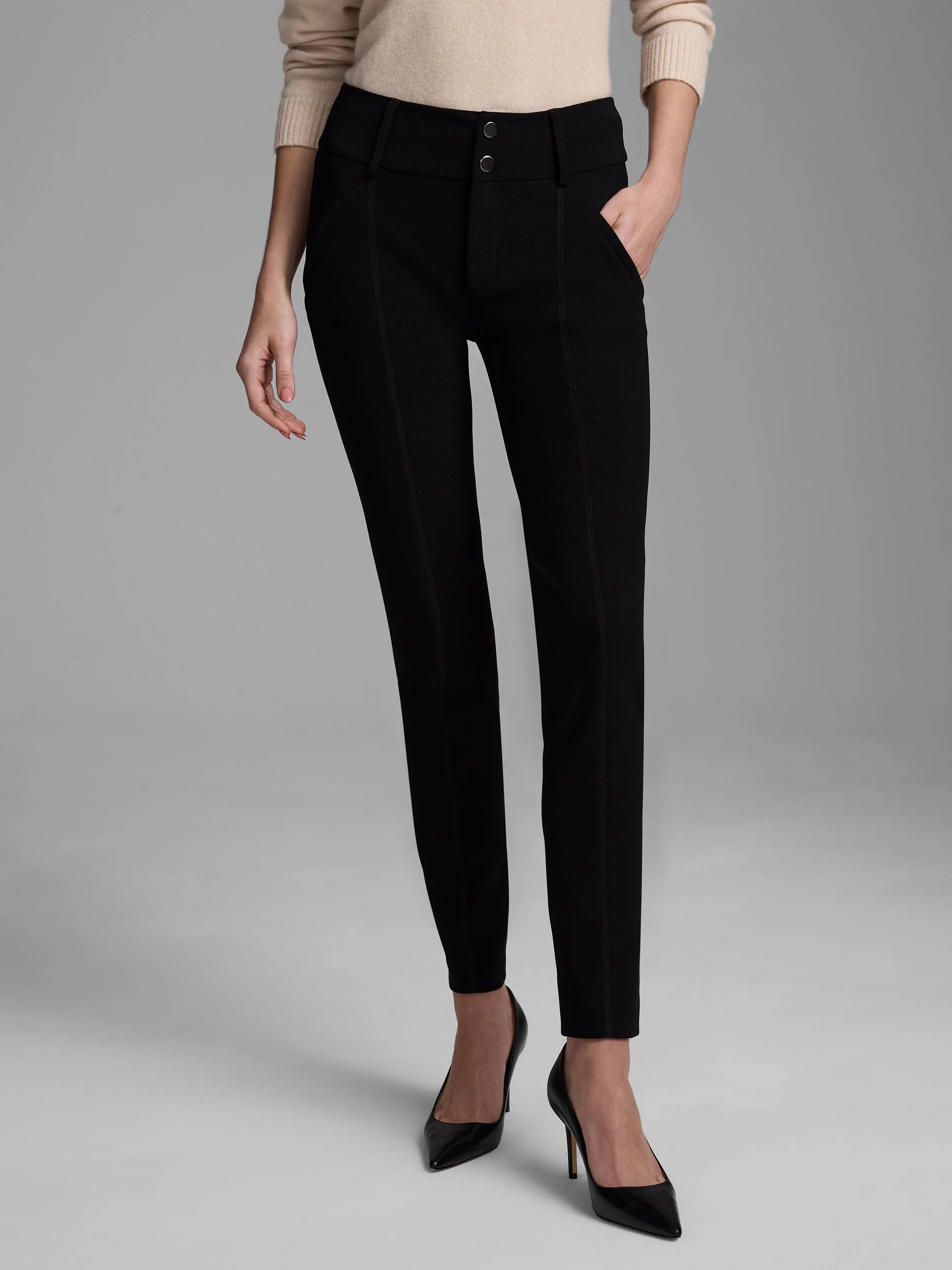 Black slim scuba knit pants, high-waisted, with two silver buttons and stitched vertical front seams.