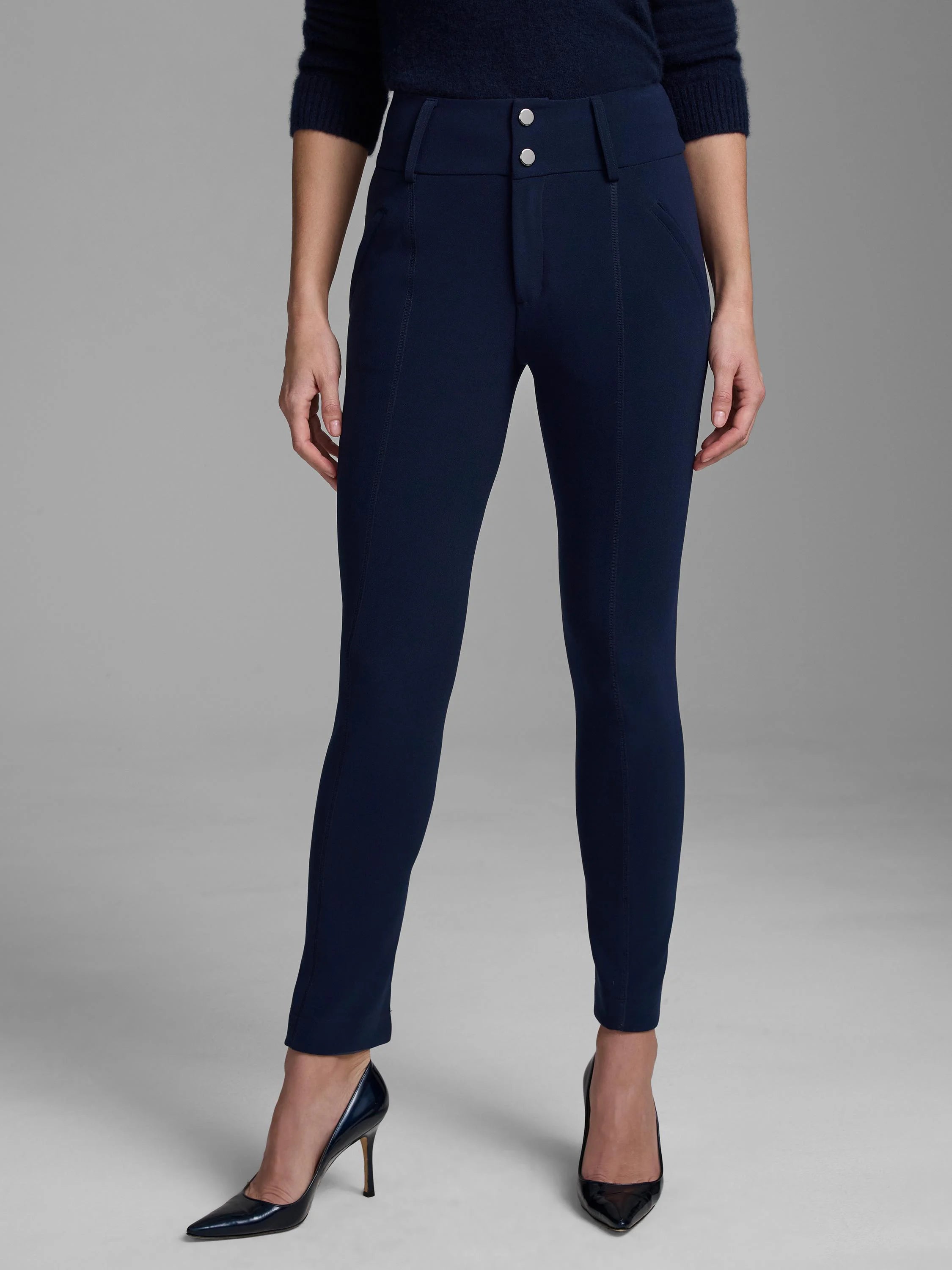 Navy high-waisted slim pants with two prominent silver buttons and vertical leg seams.