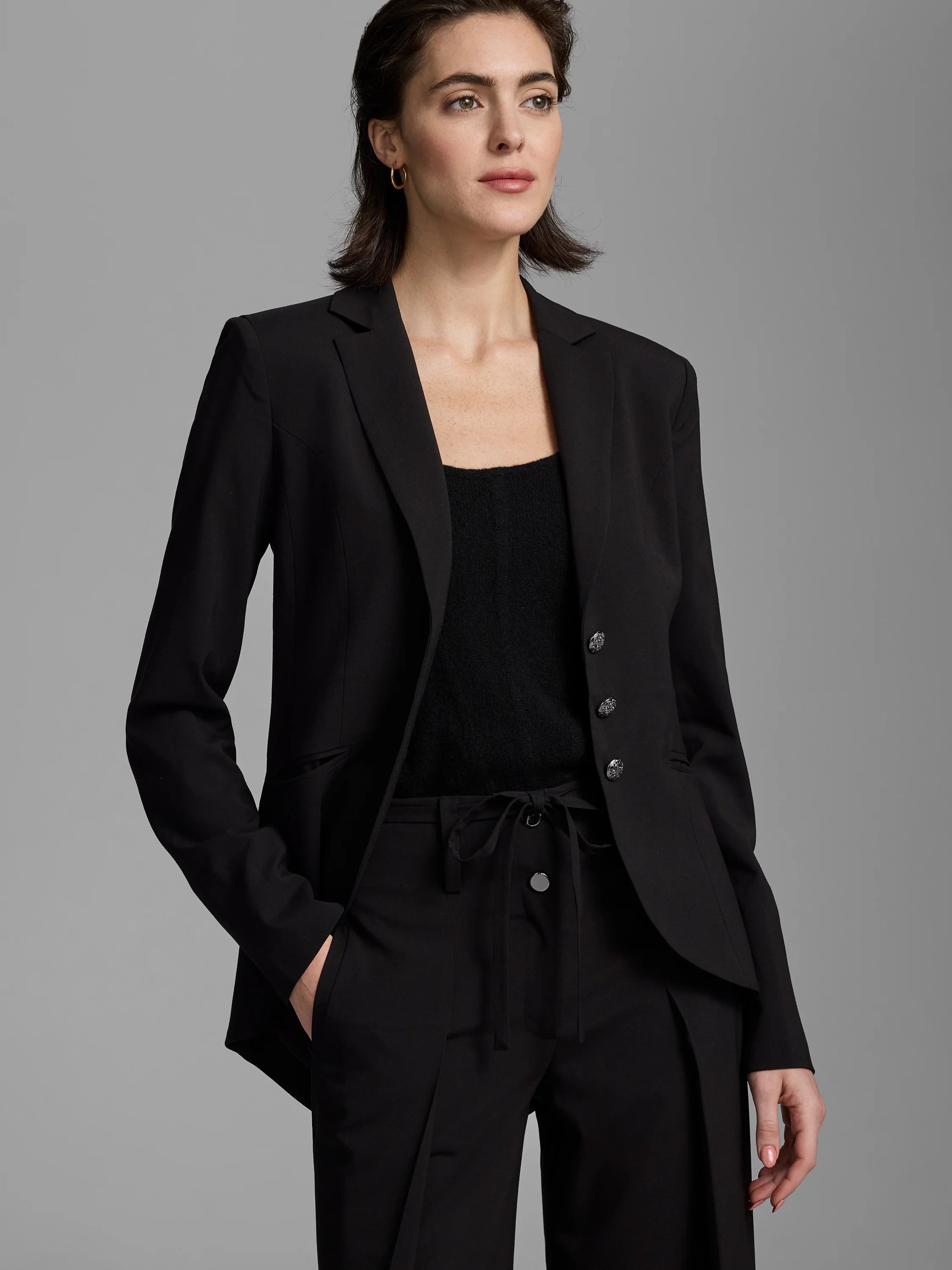 Black single-breasted blazer with classic lapels and three round, decorative dark metal buttons.
