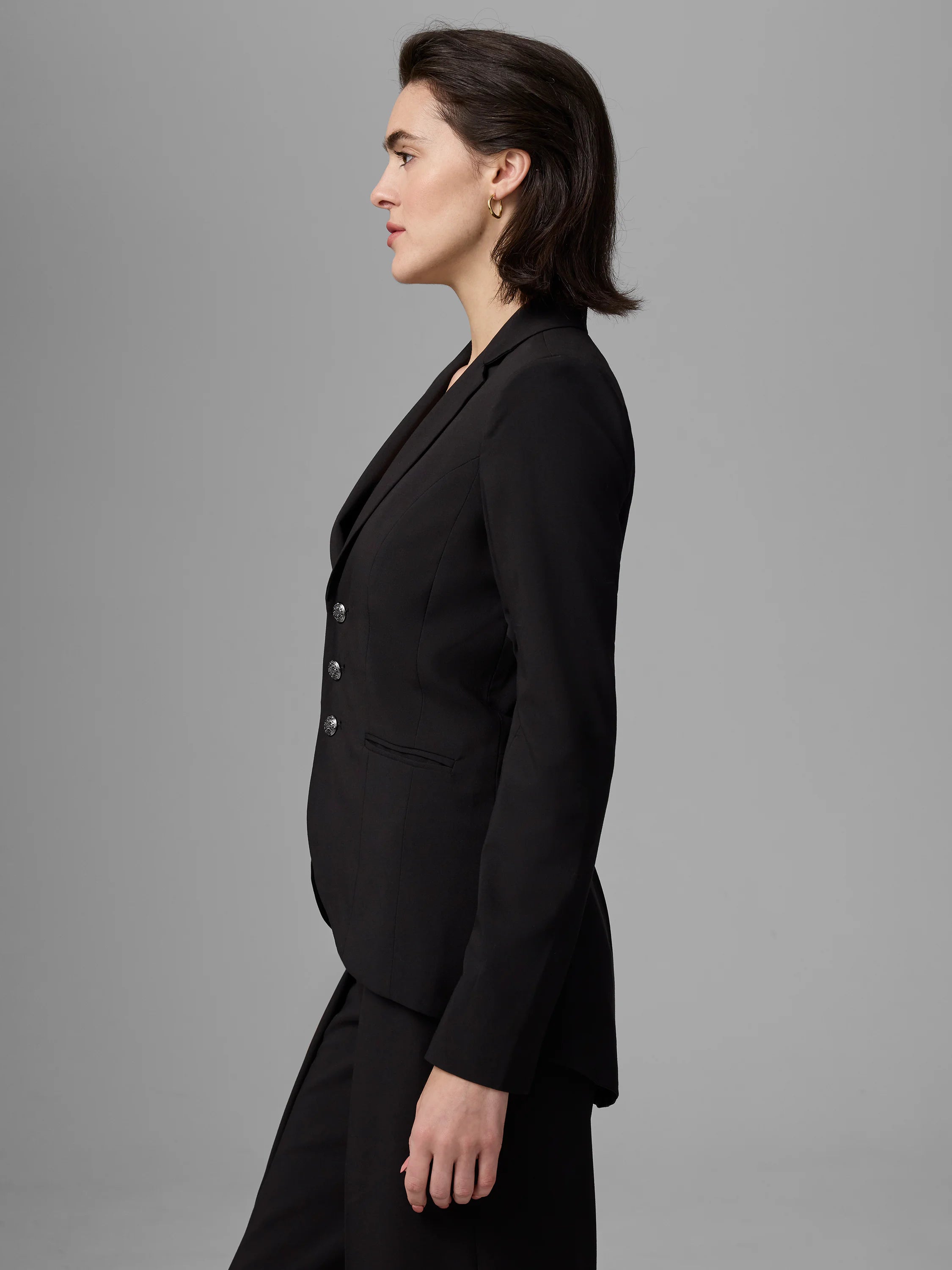 Black double-breasted blazer with notched lapels, two rows of ornate silver buttons, and flap pockets.
