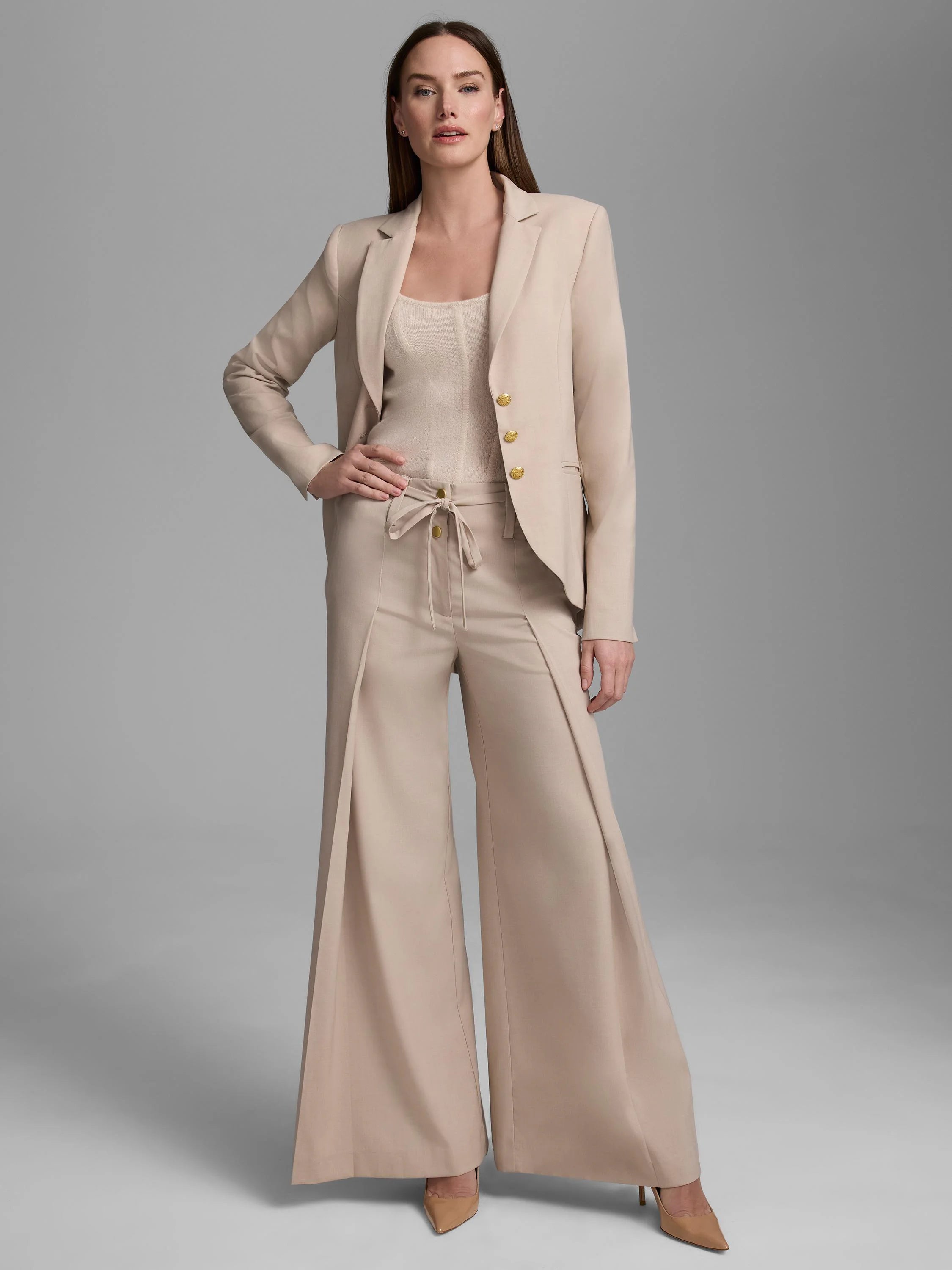 Beige blazer with gold-tone buttons and notched lapels. Worn with matching wide-leg pants and a ribbed tank.