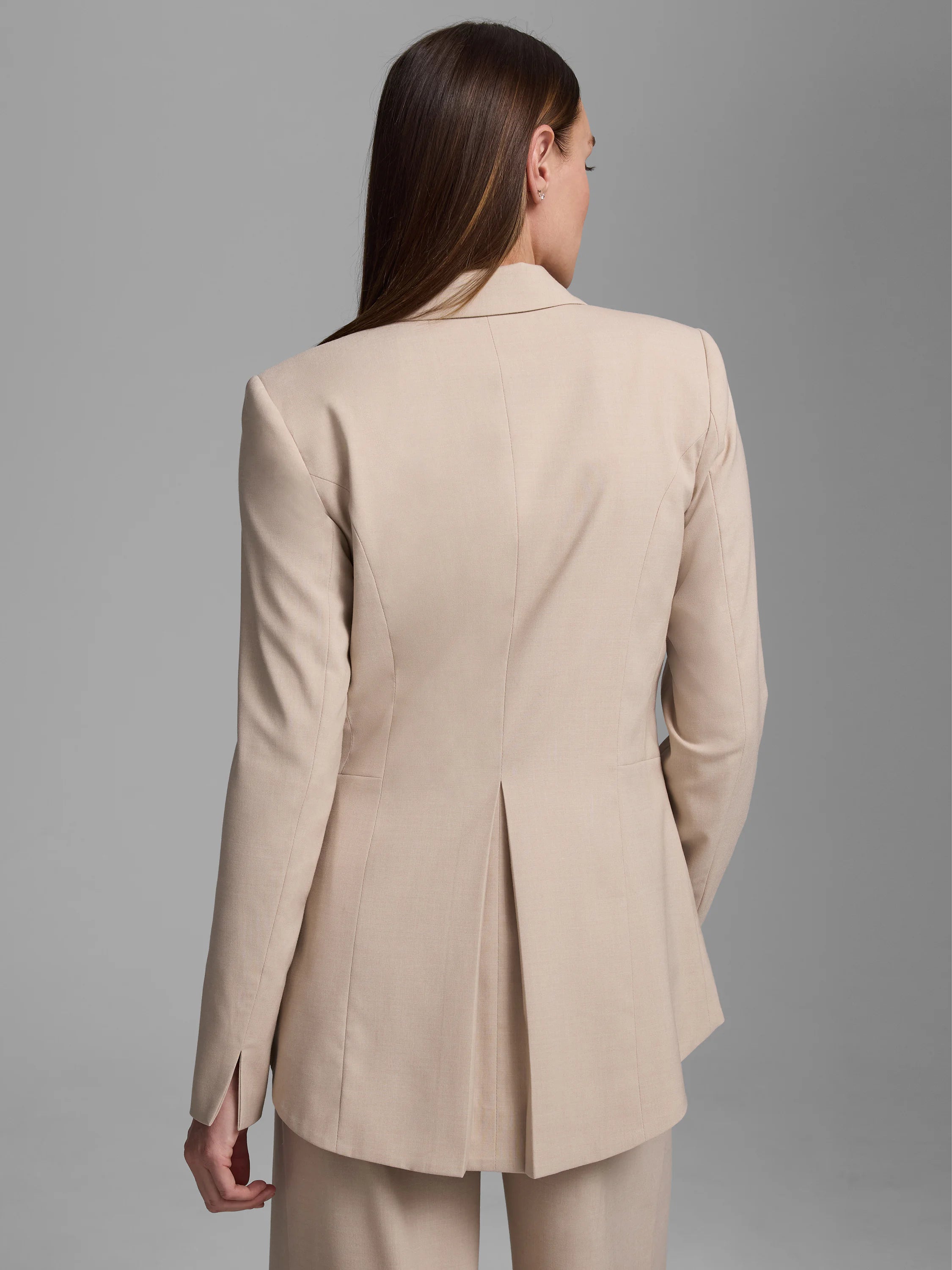 Light beige tailored blazer seen from behind, featuring a center back vent and split cuffs.