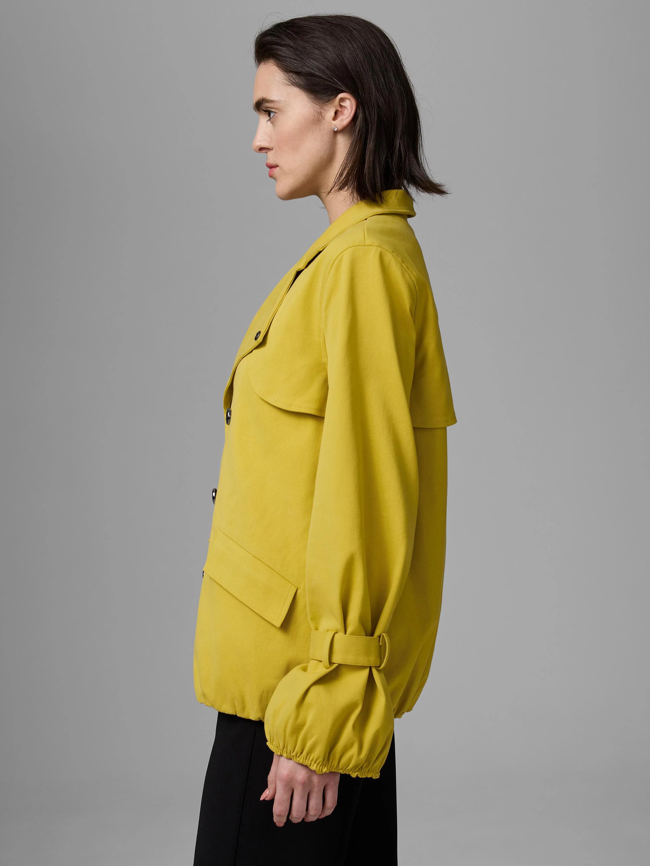 Mustard yellow twill trench with shoulder flaps, double-breasted front, and voluminous gathered sleeves.