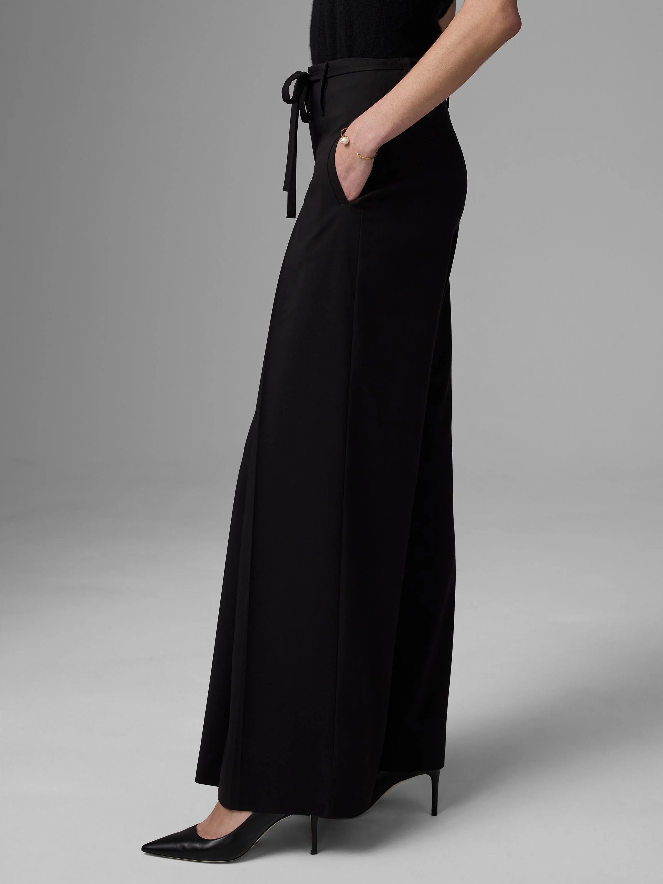 Black wide-leg apron pants with a high tie-waist.