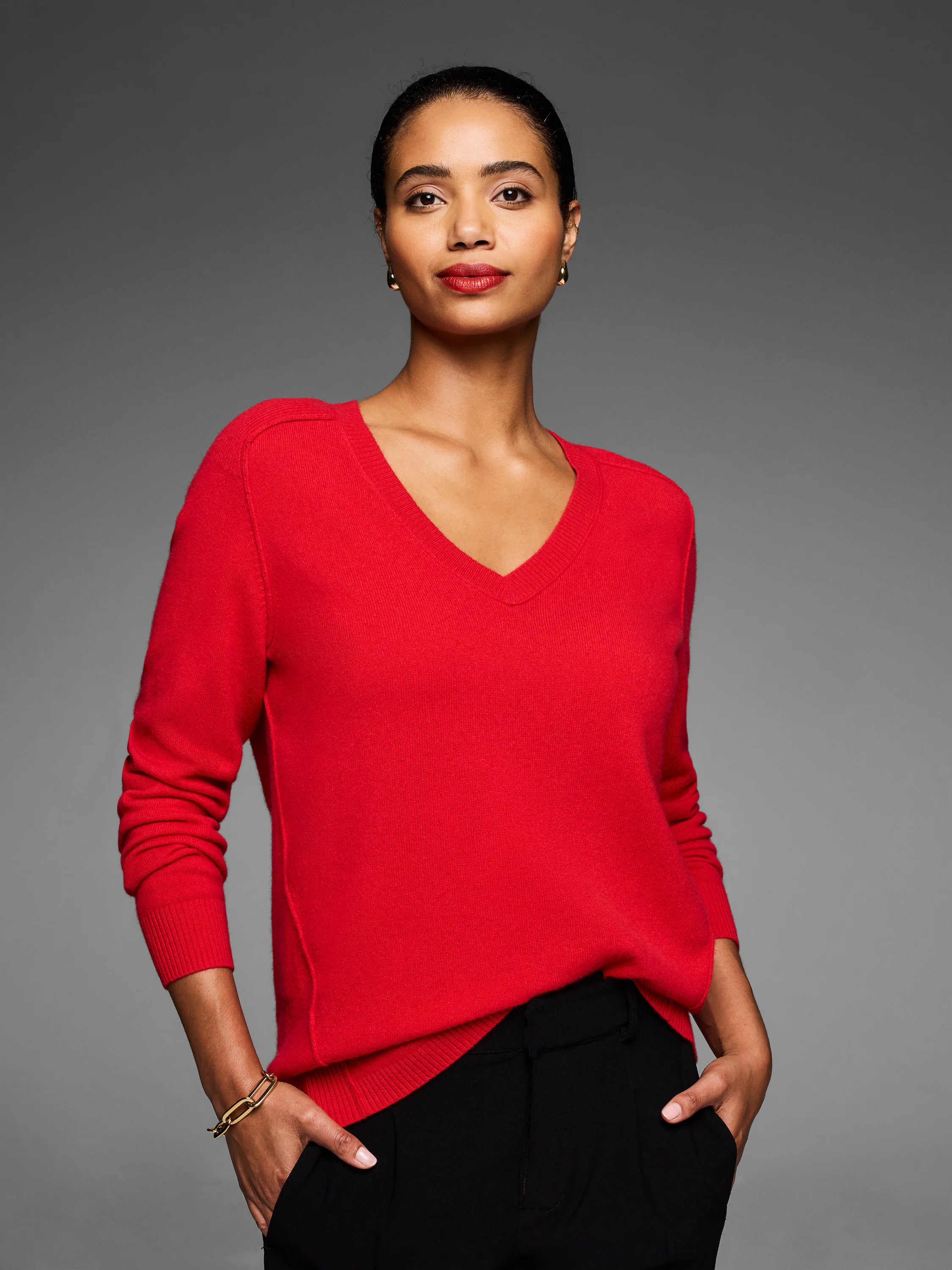 Red V-neck sweater on a model. Features ribbed trim at neck & cuffs, fine knit texture, and raglan sleeves.