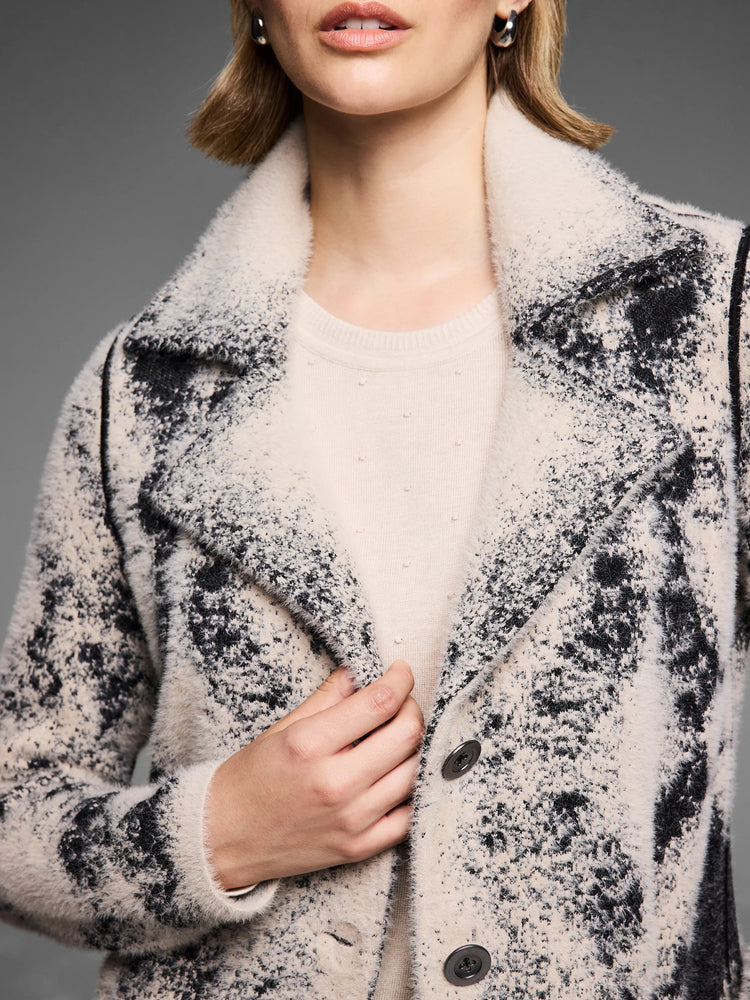 Cream & black textured knit coat with fuzzy speckled pattern, lapel collar, & visible dark buttons.