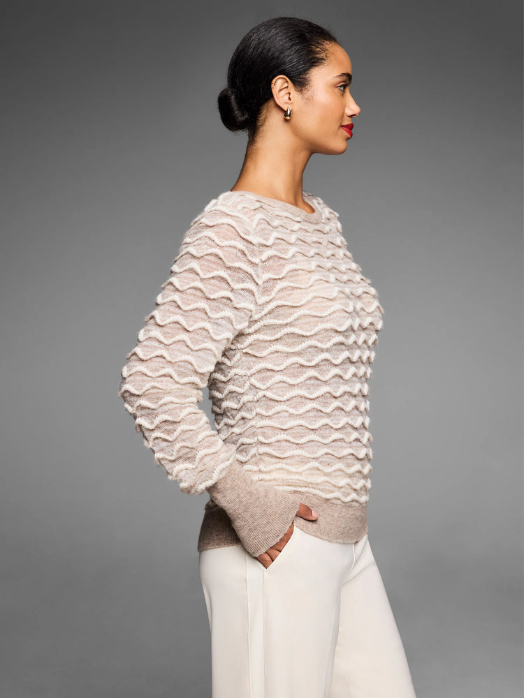Light beige sweater with raised cream wave stitches, ribbed cuffs, and hem. Model shown from the side.
