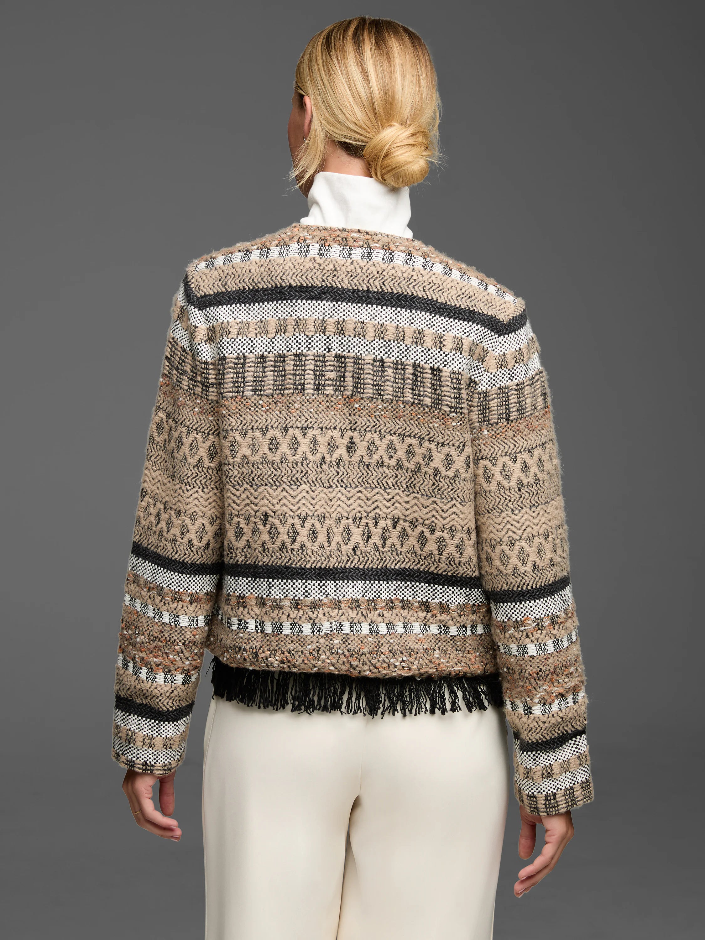 Beige knit jacket with black & white woven geometric patterns, horizontal stripes, & black fringe hem.