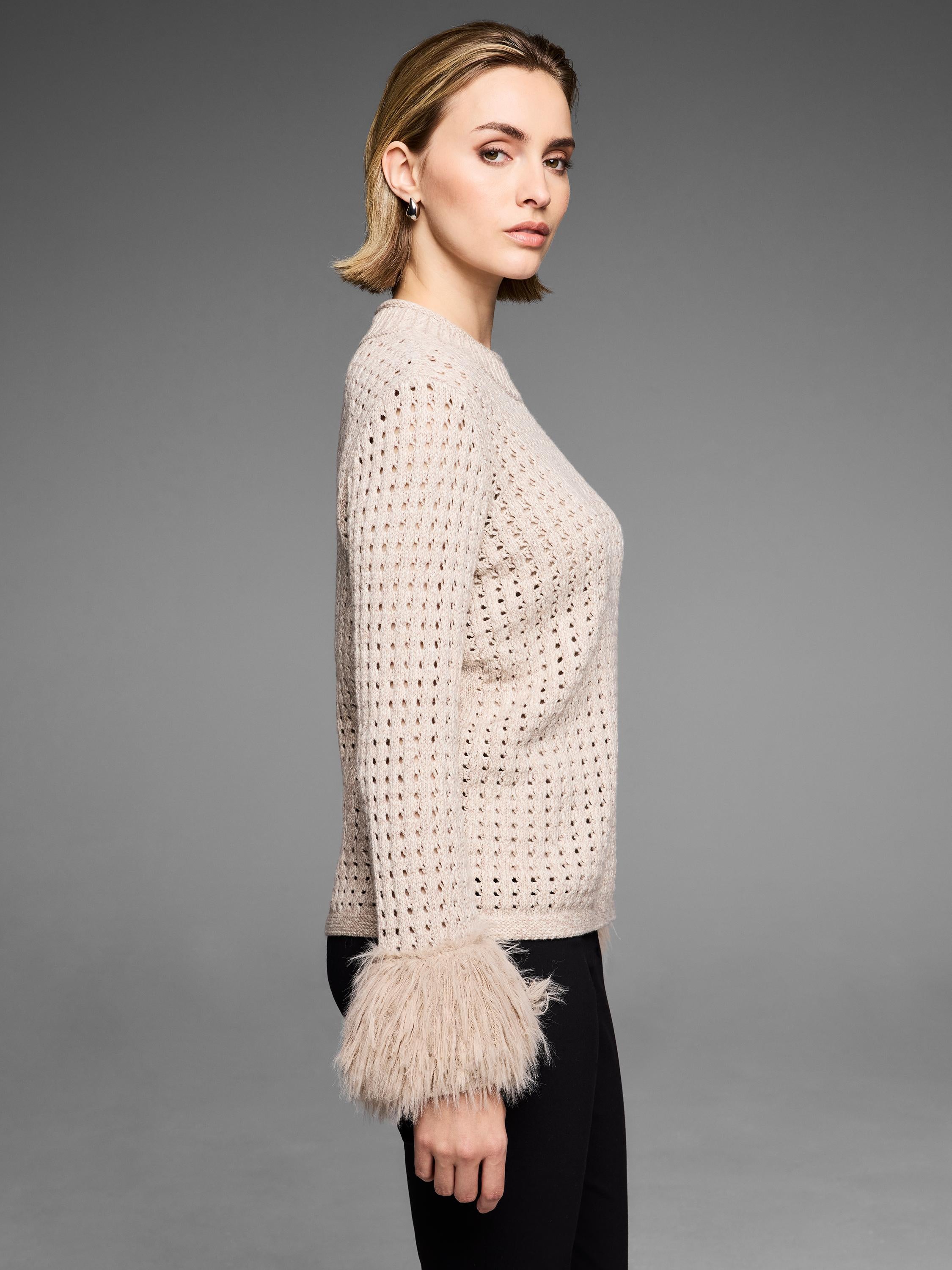 Fitted beige open-knit sweater featuring dramatic shaggy faux fur cuffs on the sleeves.