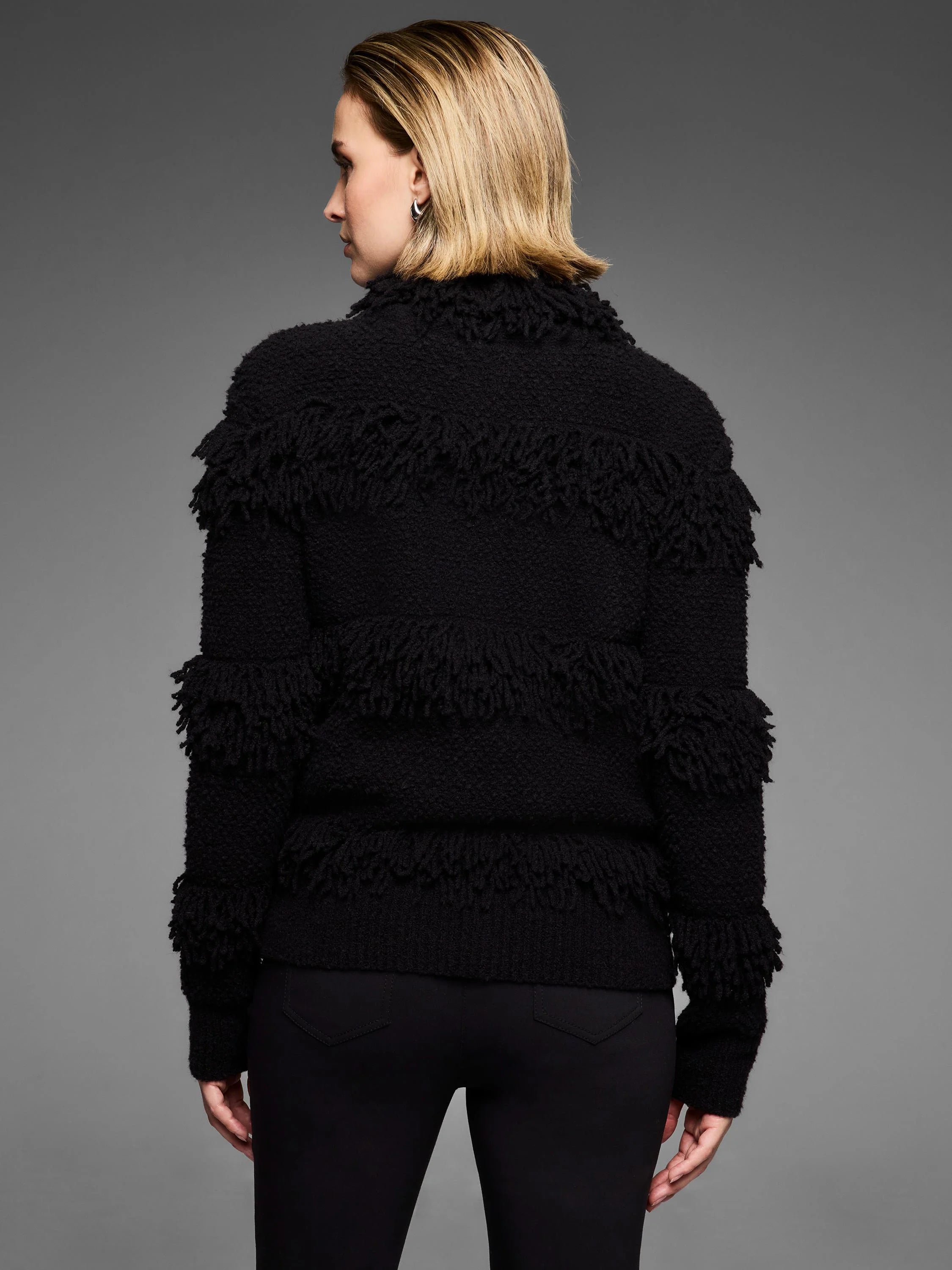 Black placed fringe jacket on a model, seen from the back. Features textured fabric with horizontal fringe bands.