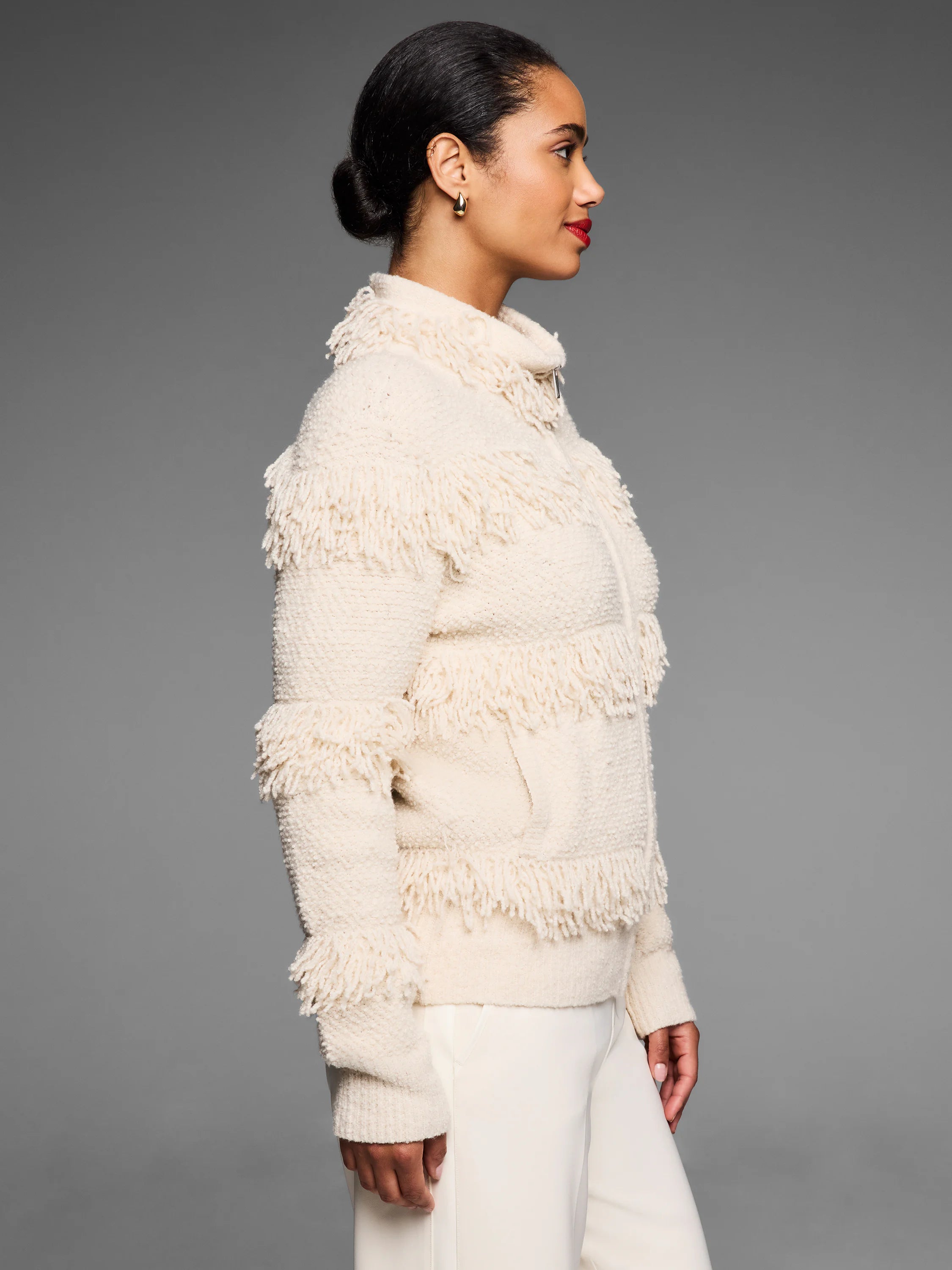 Cream jacket with horizontal fringe rows, textured knit fabric, stand-up collar, and zipper.