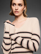 Cream V-neck sweater with horizontal black and light brown stripes, speckled with tiny sparkles.
