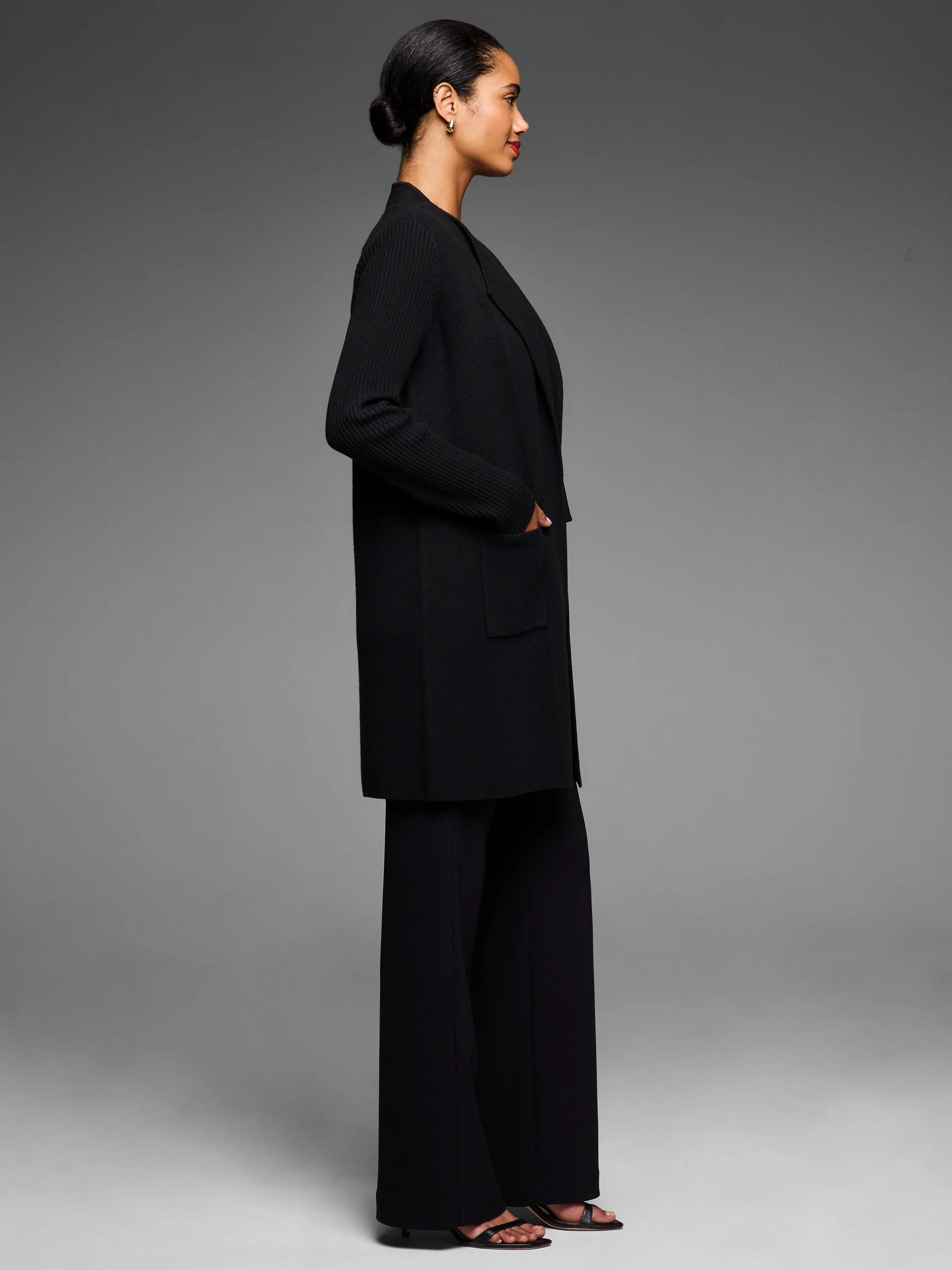 Black long open-front coat with ribbed sleeves and two front patch pockets.