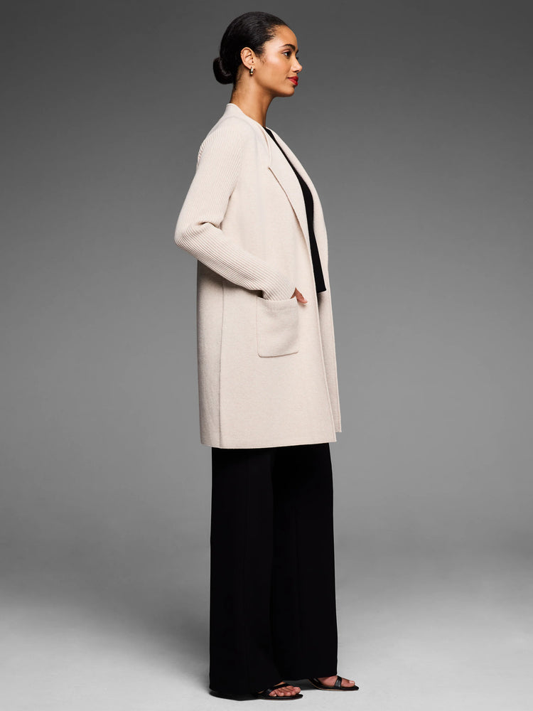 Cream open-front knit coat, knee-length, with ribbed long sleeves and two front patch pockets.