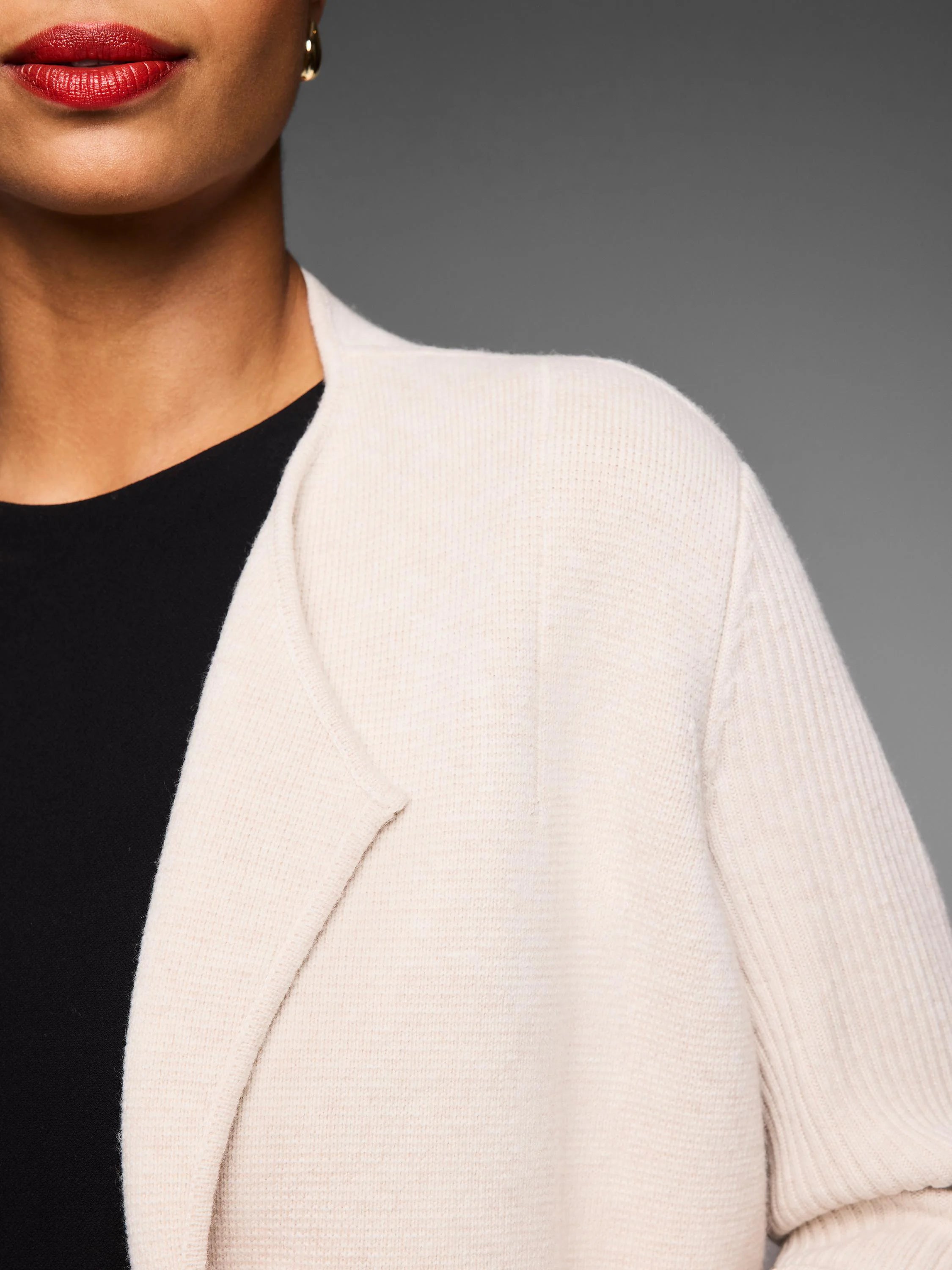 Cream cashmere blend coat with ribbed knit texture and open front lapel, worn over a black top.