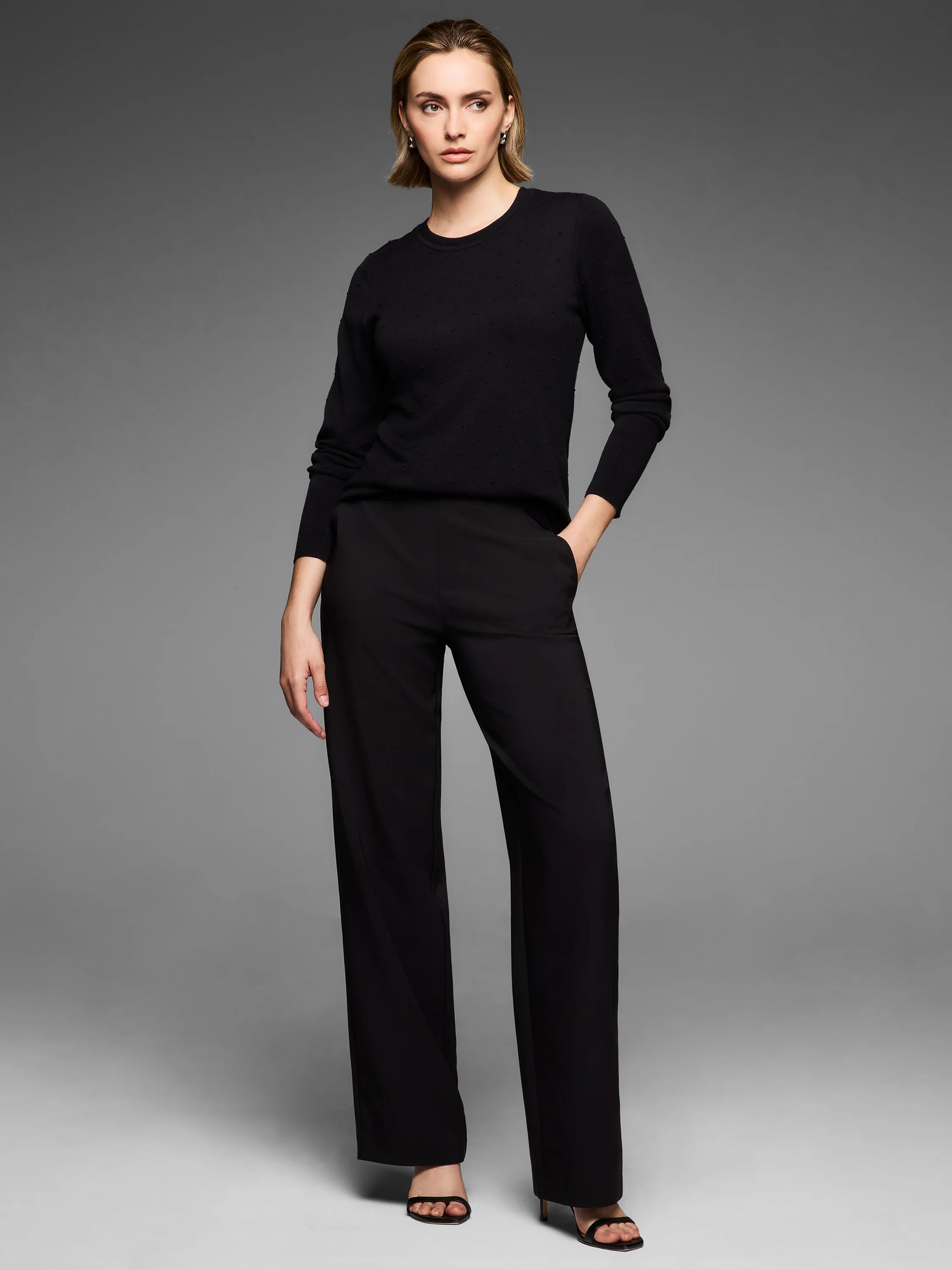 Black long-sleeved crew-neck sweater with a subtle dotty texture.