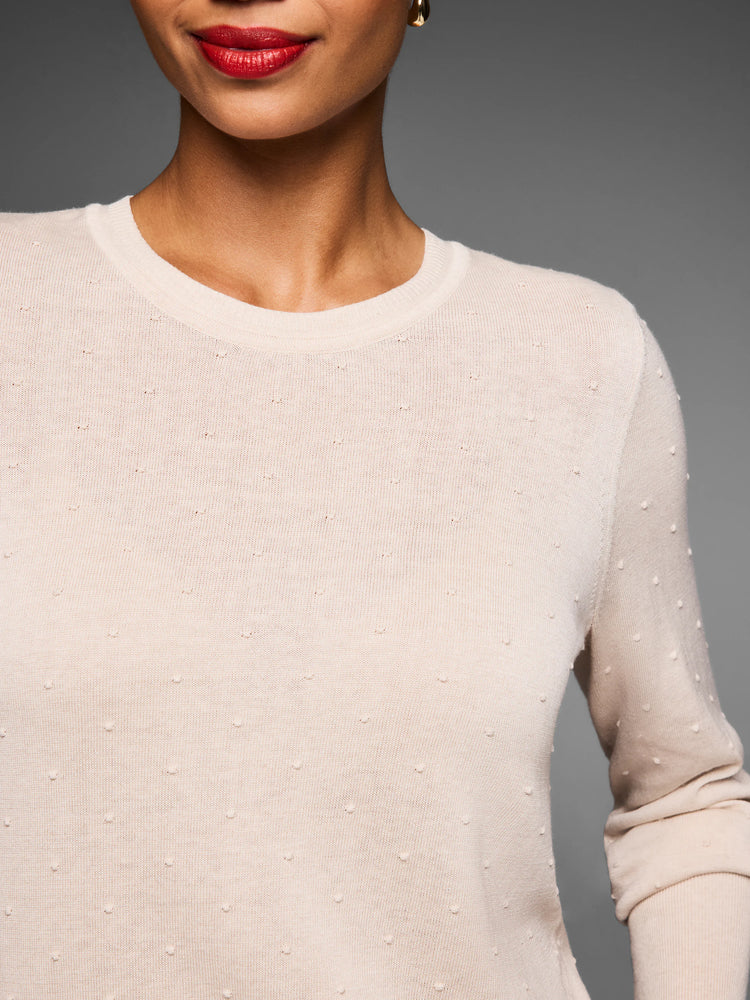 Cream sweater with subtle raised dot texture. Close-up shows crew neck and sleeves.