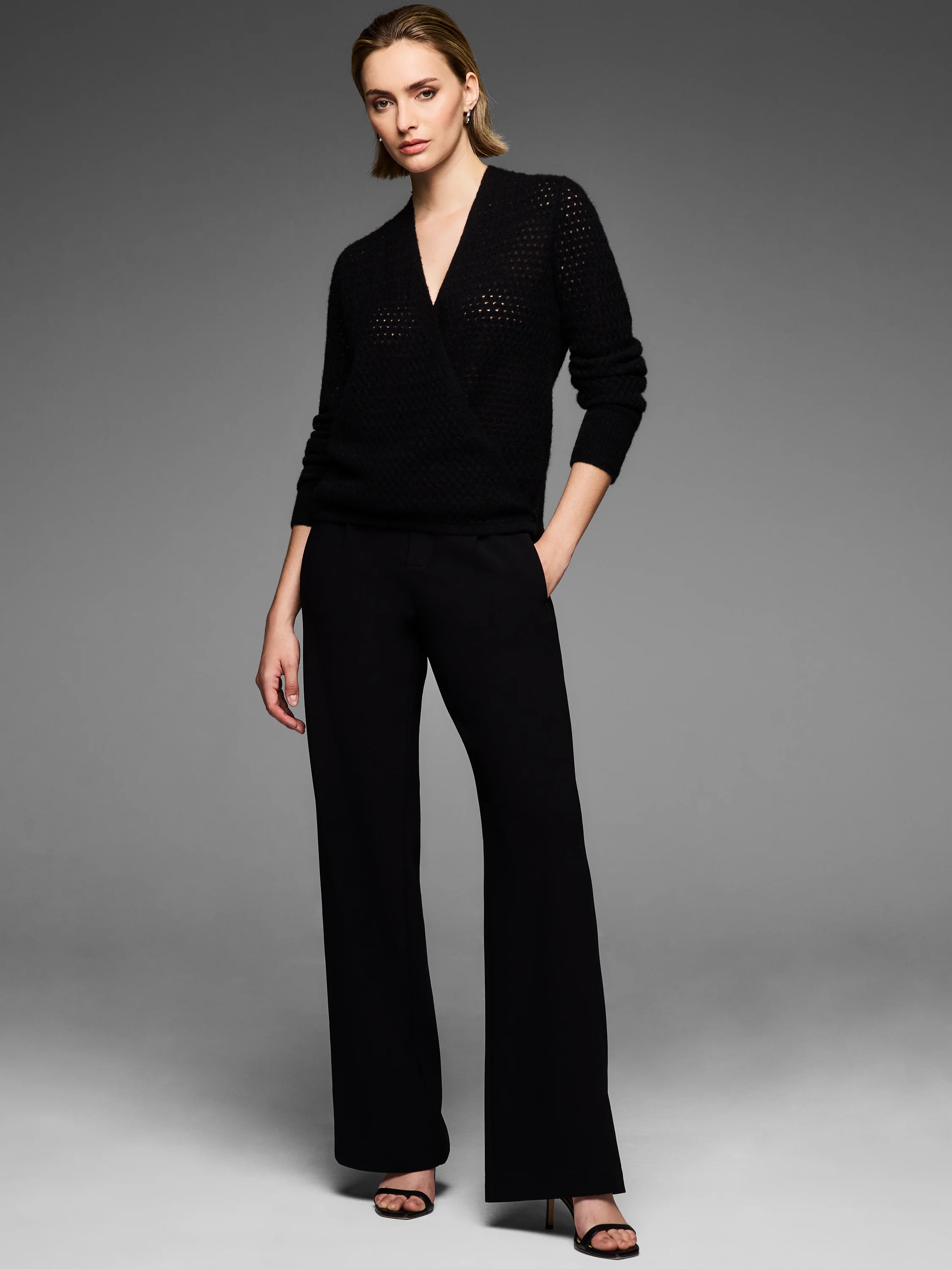 Black pointelle knit cardigan, styled as a V-neck wrap. Features subtle openwork texture.