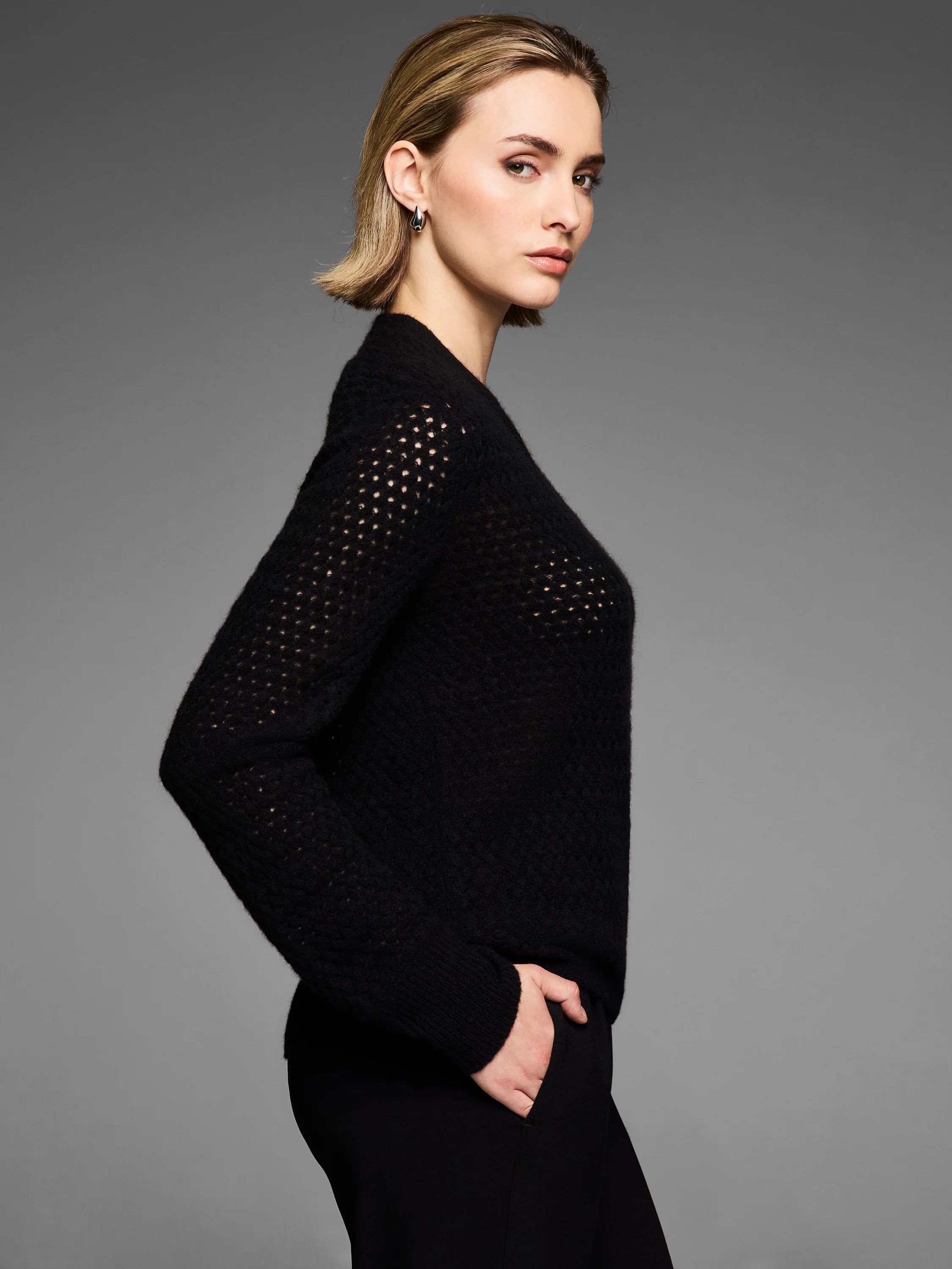 Black cashmere cardigan with open pointelle knit on sleeves & shoulders, styled as a sweater.