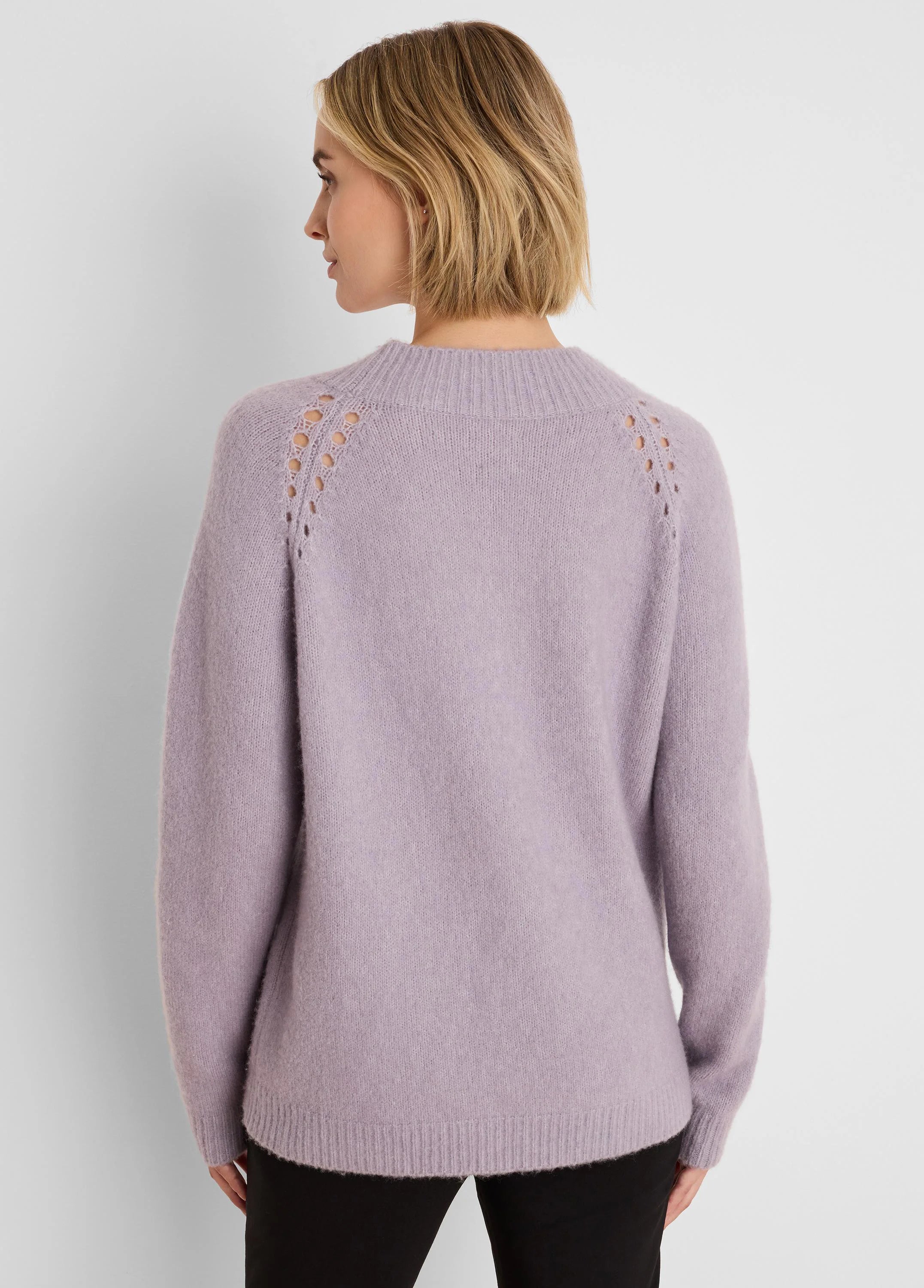 Back view: Lavender fuzzy sweater with ribbed mock neck and decorative eyelets along the raglan shoulders.