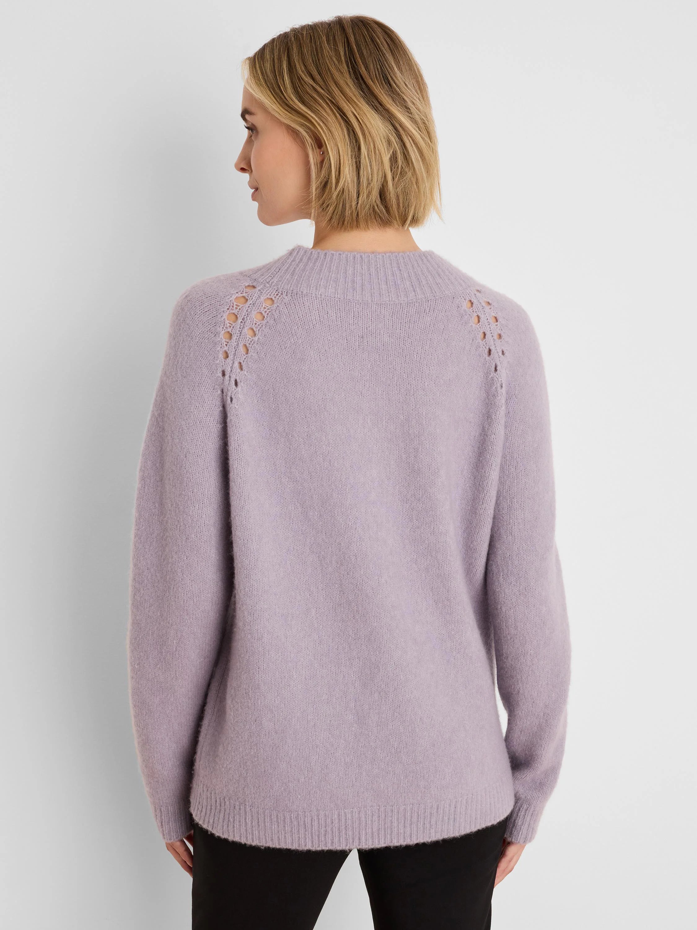 Back view: Lavender fuzzy sweater with ribbed mock neck and decorative eyelets along the raglan shoulders.