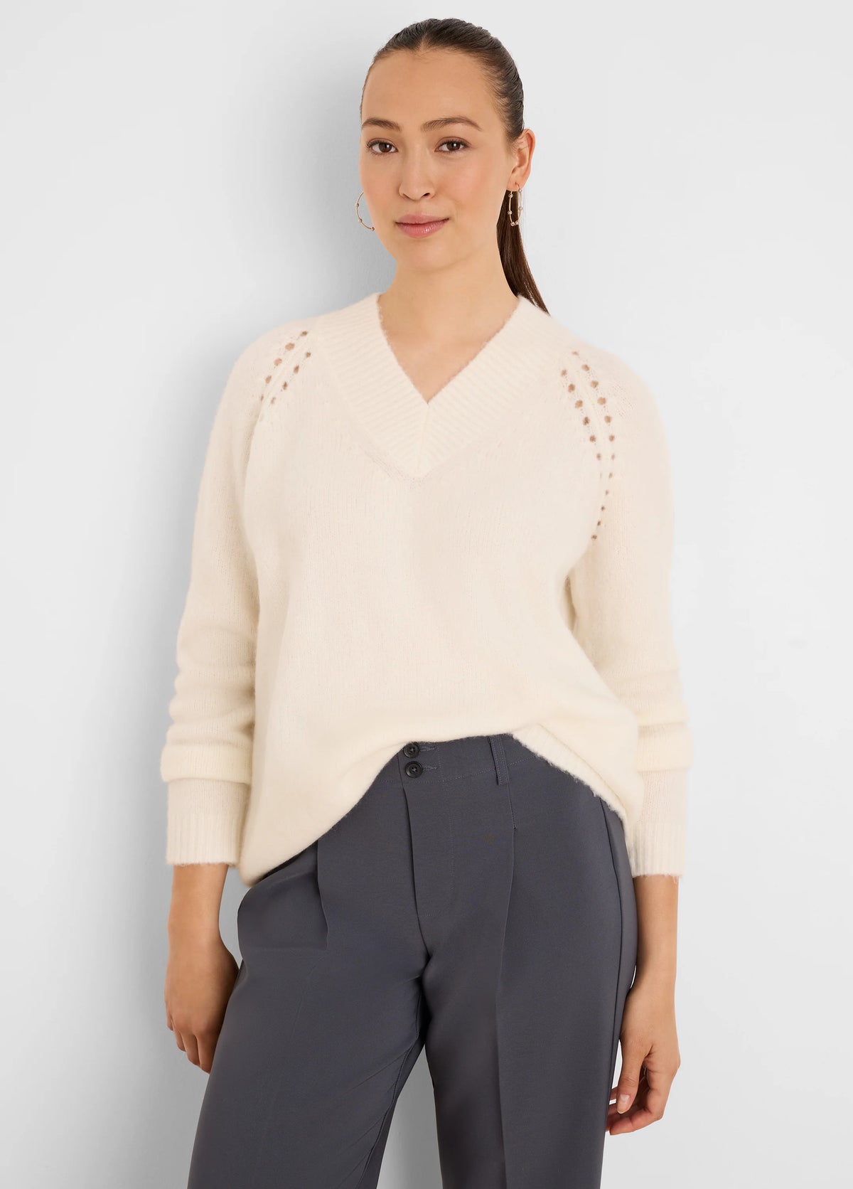 Cream, fuzzy V-neck sweater with raglan eyelet shoulder details and ribbed cuffs.