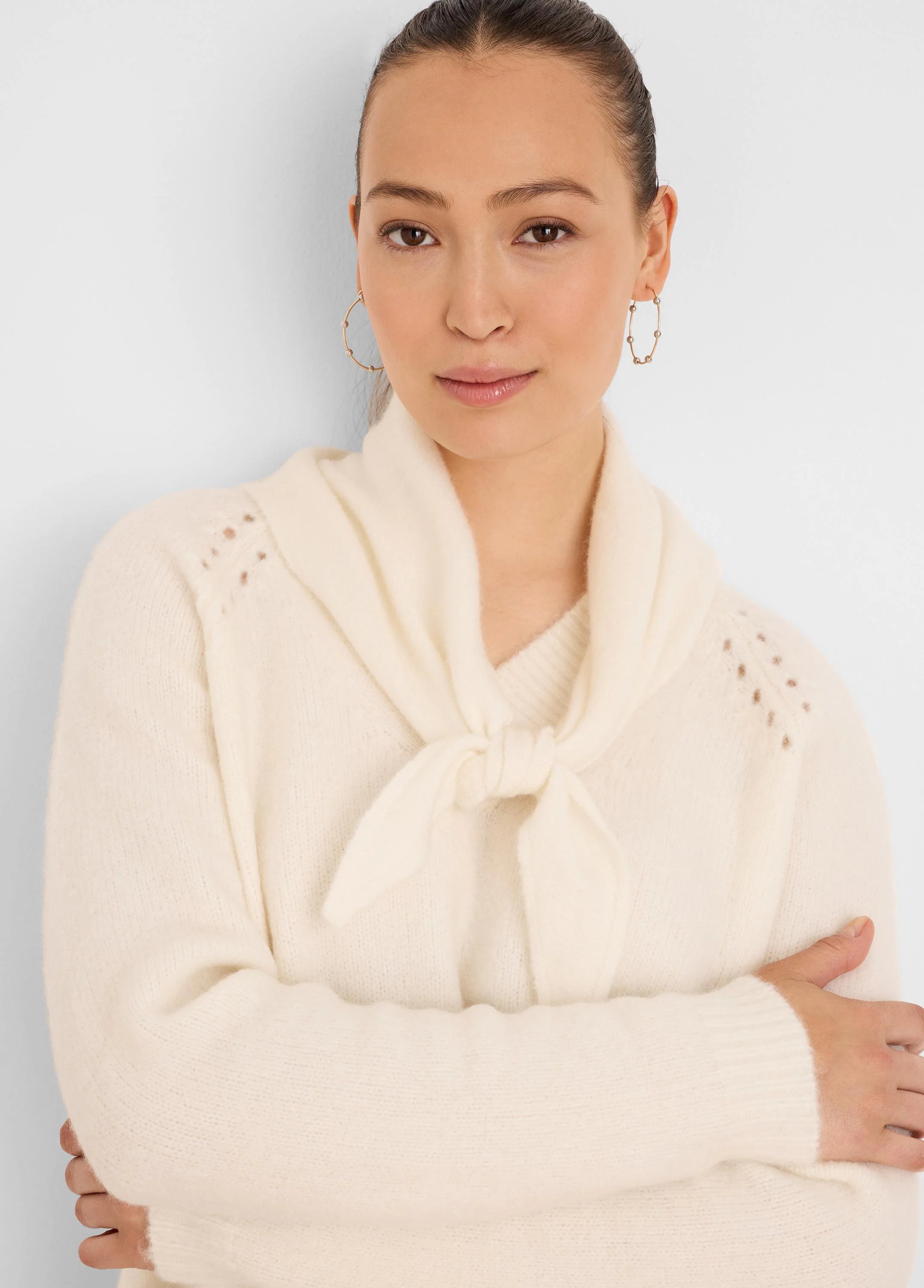 Cream V-neck sweater featuring a tied scarf neck and decorative openwork details on the shoulders.