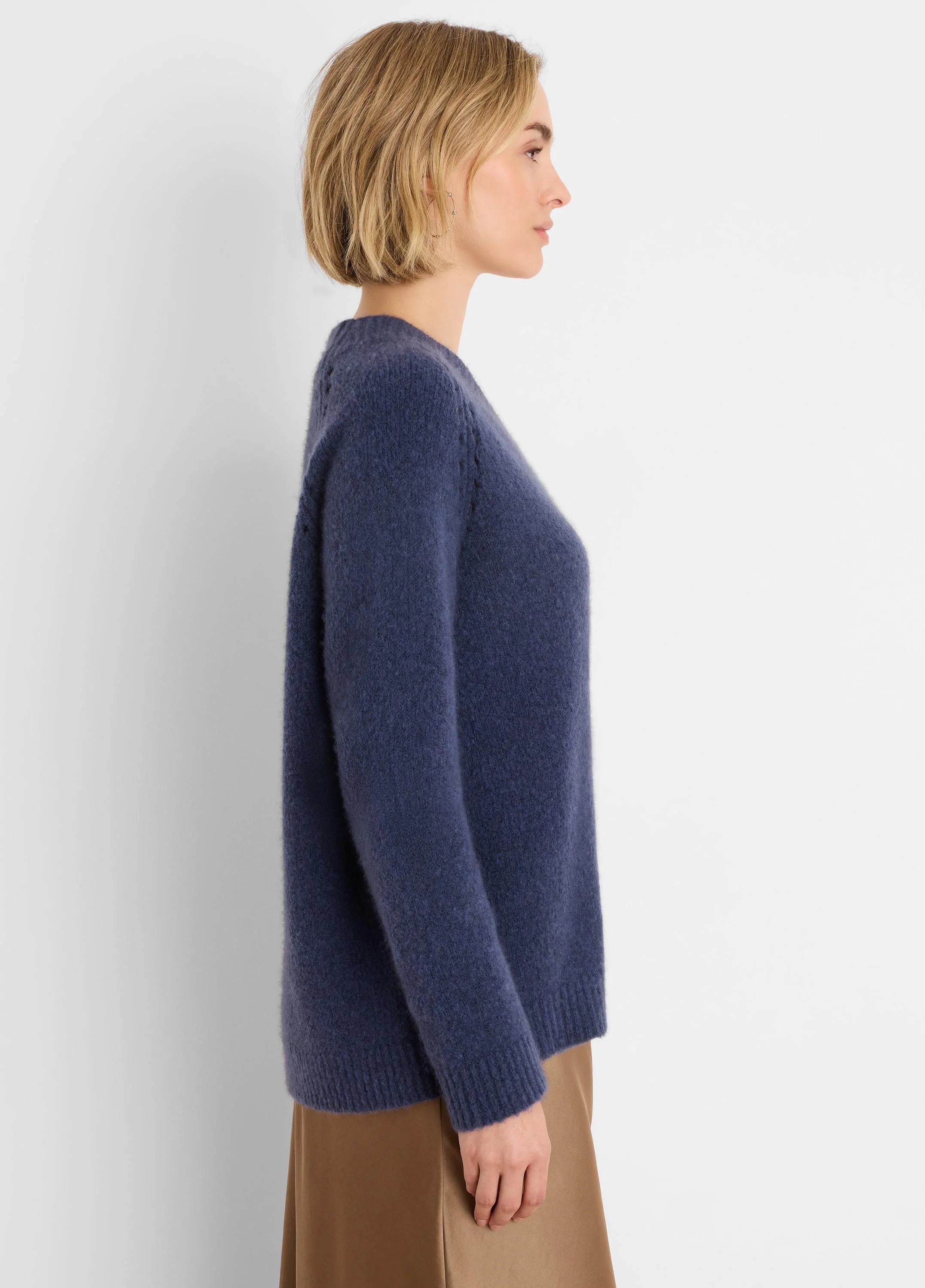 Side view of a model wearing a navy blue soft, brushed sweater with a relaxed fit. Ribbed cuffs and hem.