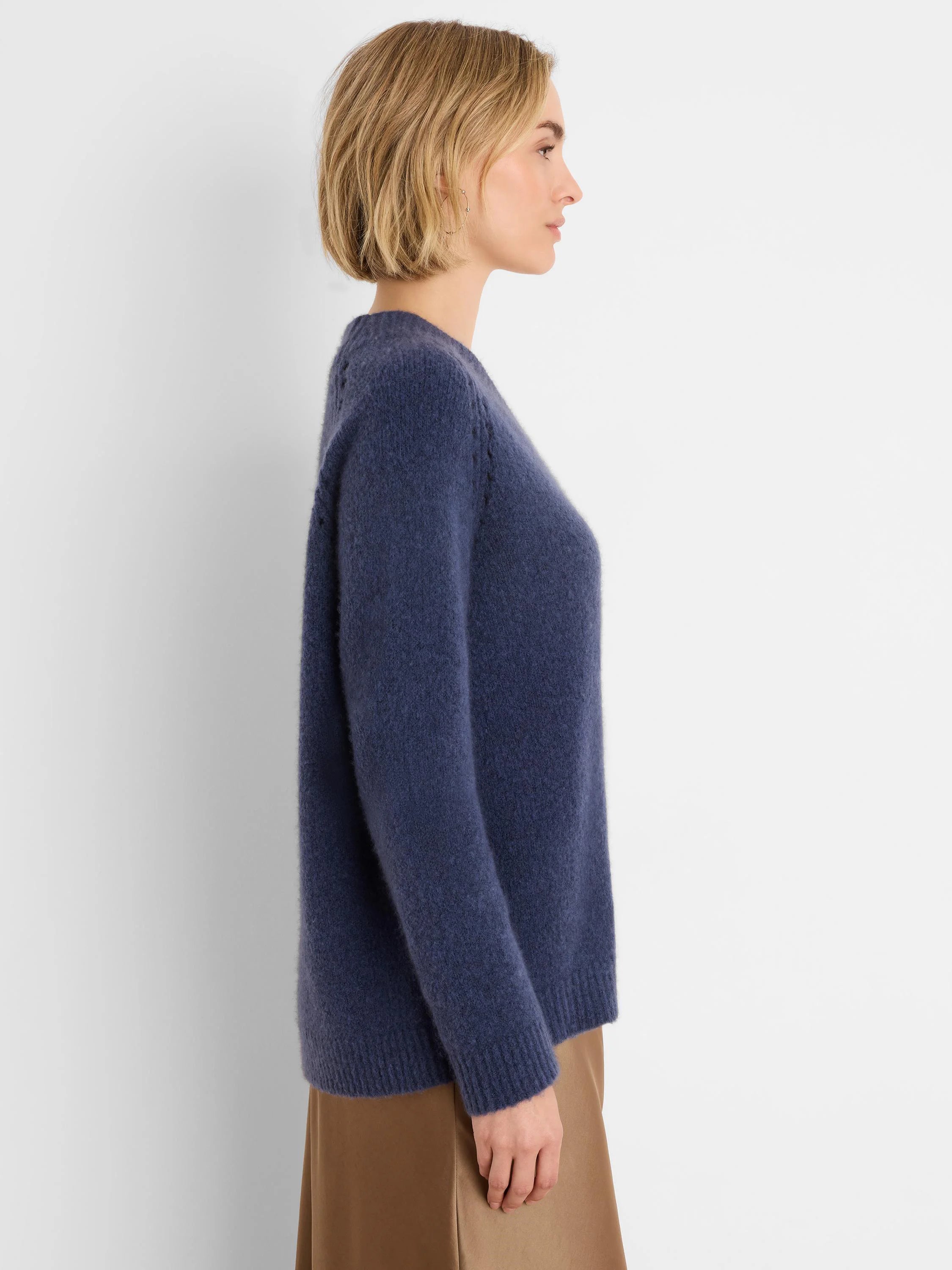 Side view of a model wearing a navy blue soft, brushed sweater with a relaxed fit. Ribbed cuffs and hem.