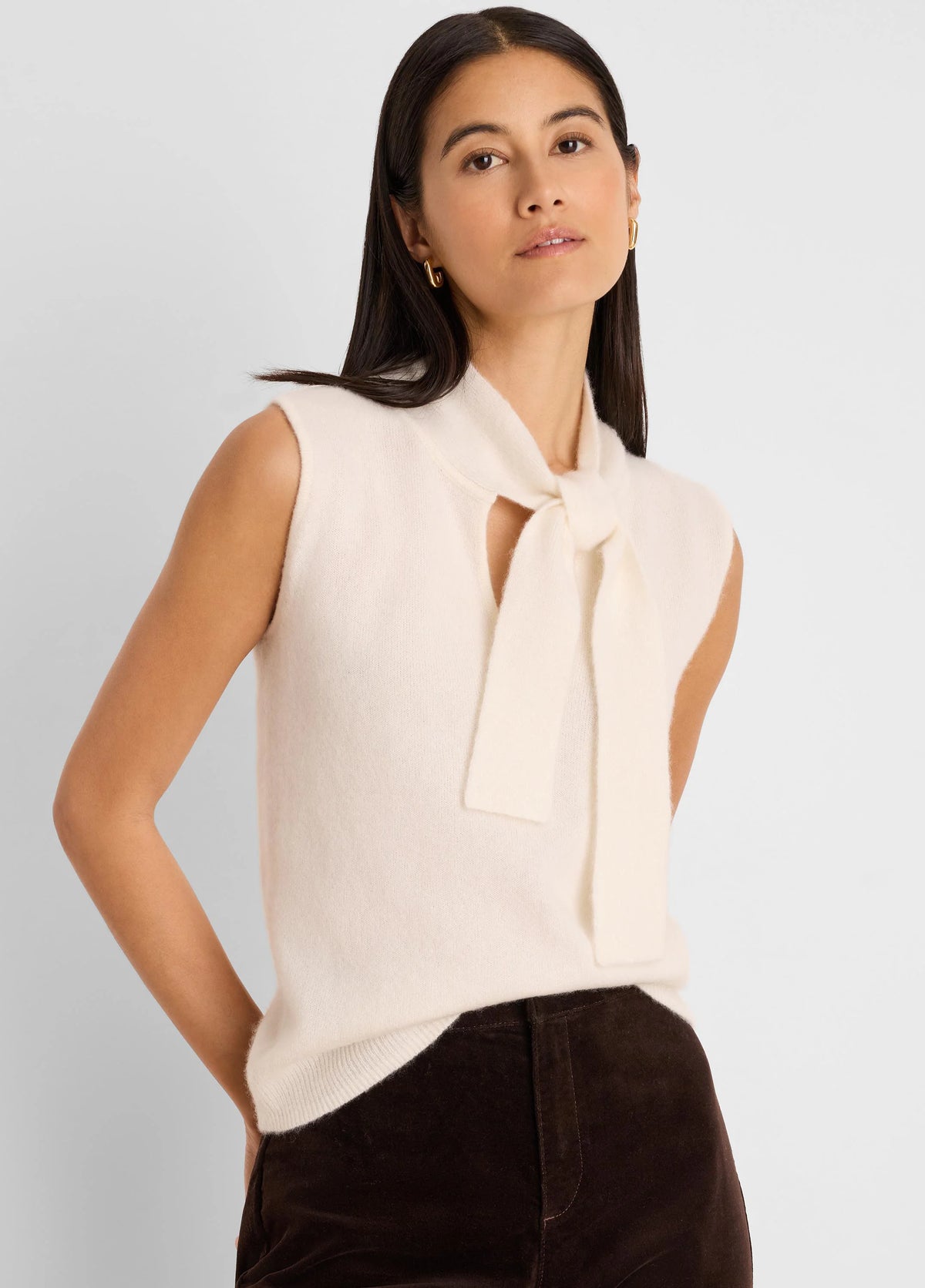 Cream sleeveless tank with a soft texture, featuring a tied bow above a V-neck opening.