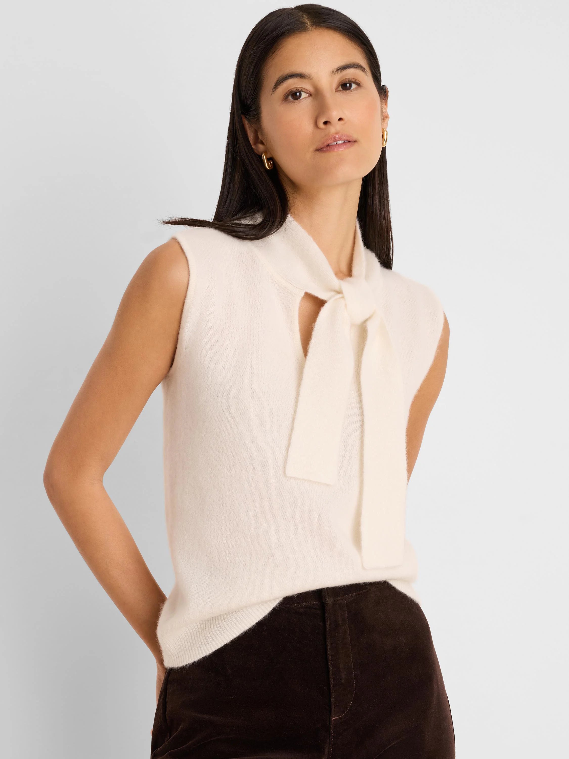 Cream sleeveless tank with a soft texture, featuring a tied bow above a V-neck opening.