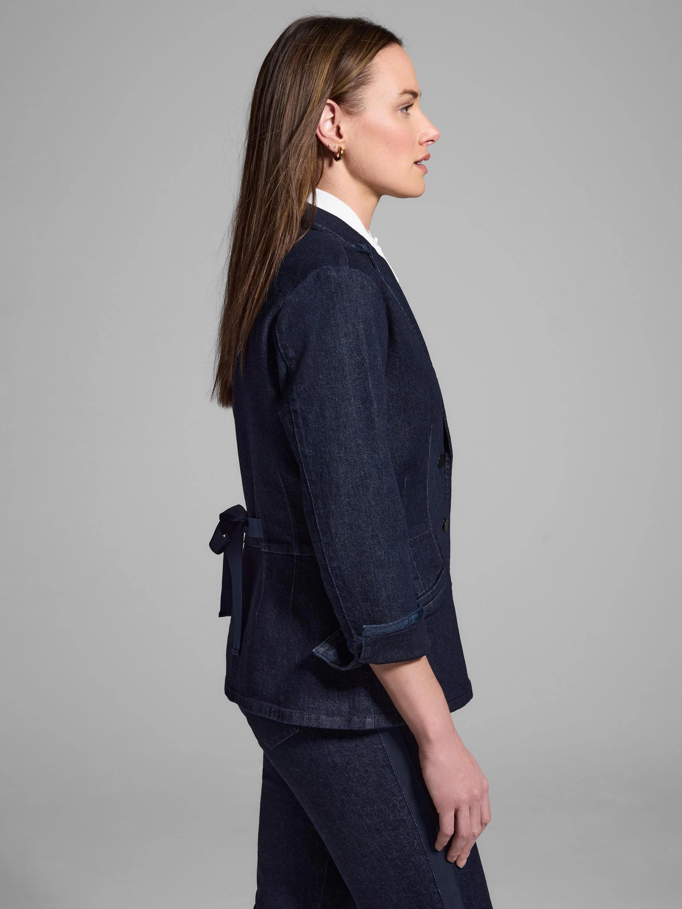 Dark wash denim blazer with a black ribbon detail at the back. Three-quarter sleeves.