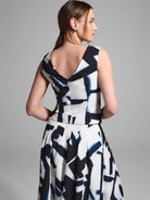 White top and skirt with an abstract blue and black print. Sleeveless top, V-neck back.  Pleated skirt.