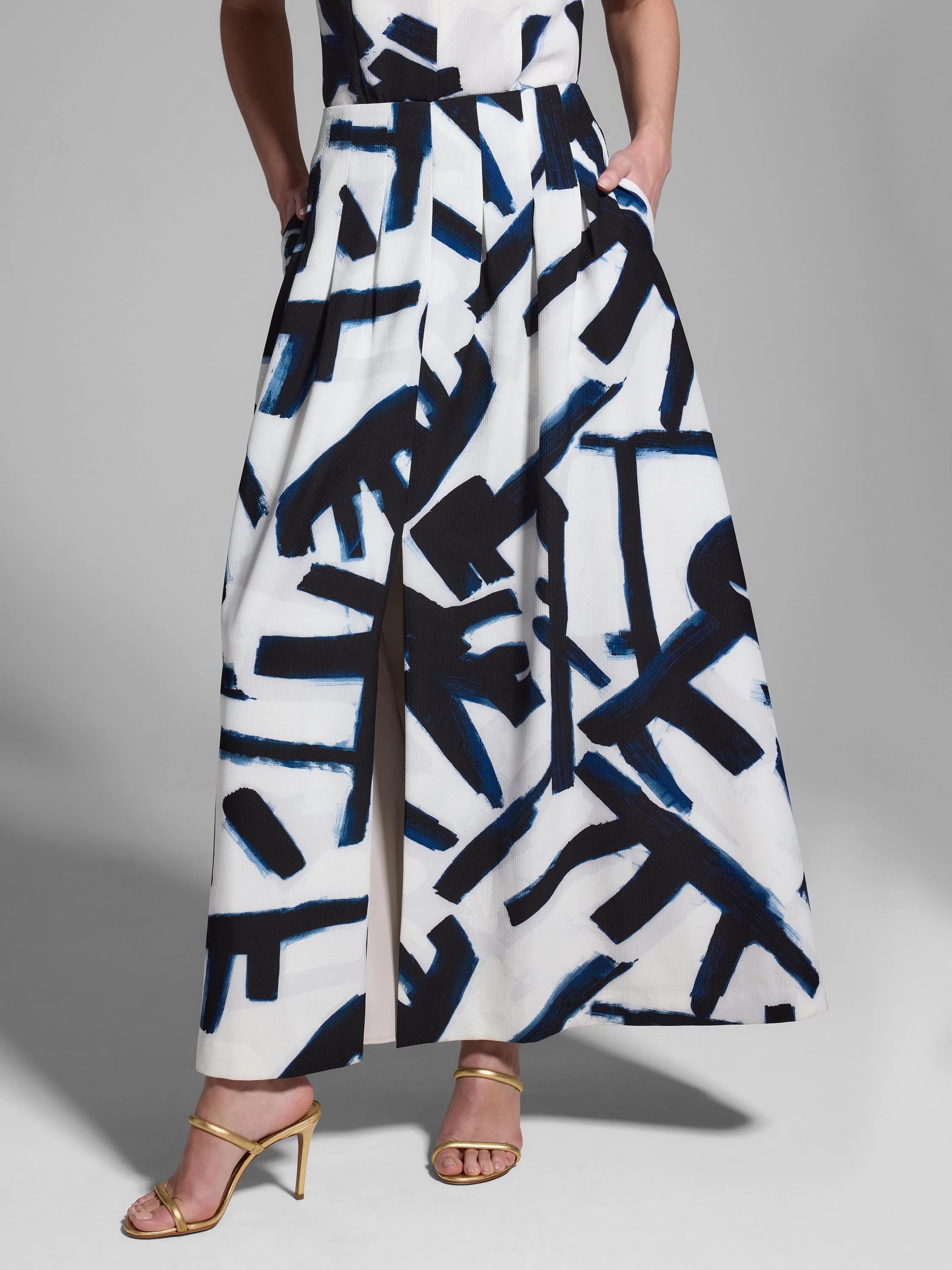 White pleated maxi skirt with a dark blue and black abstract print.  Center front slit.