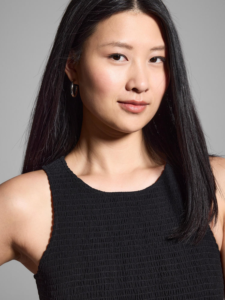 Black smocked chiffon sleeveless dress. Close-up shows textured fabric.