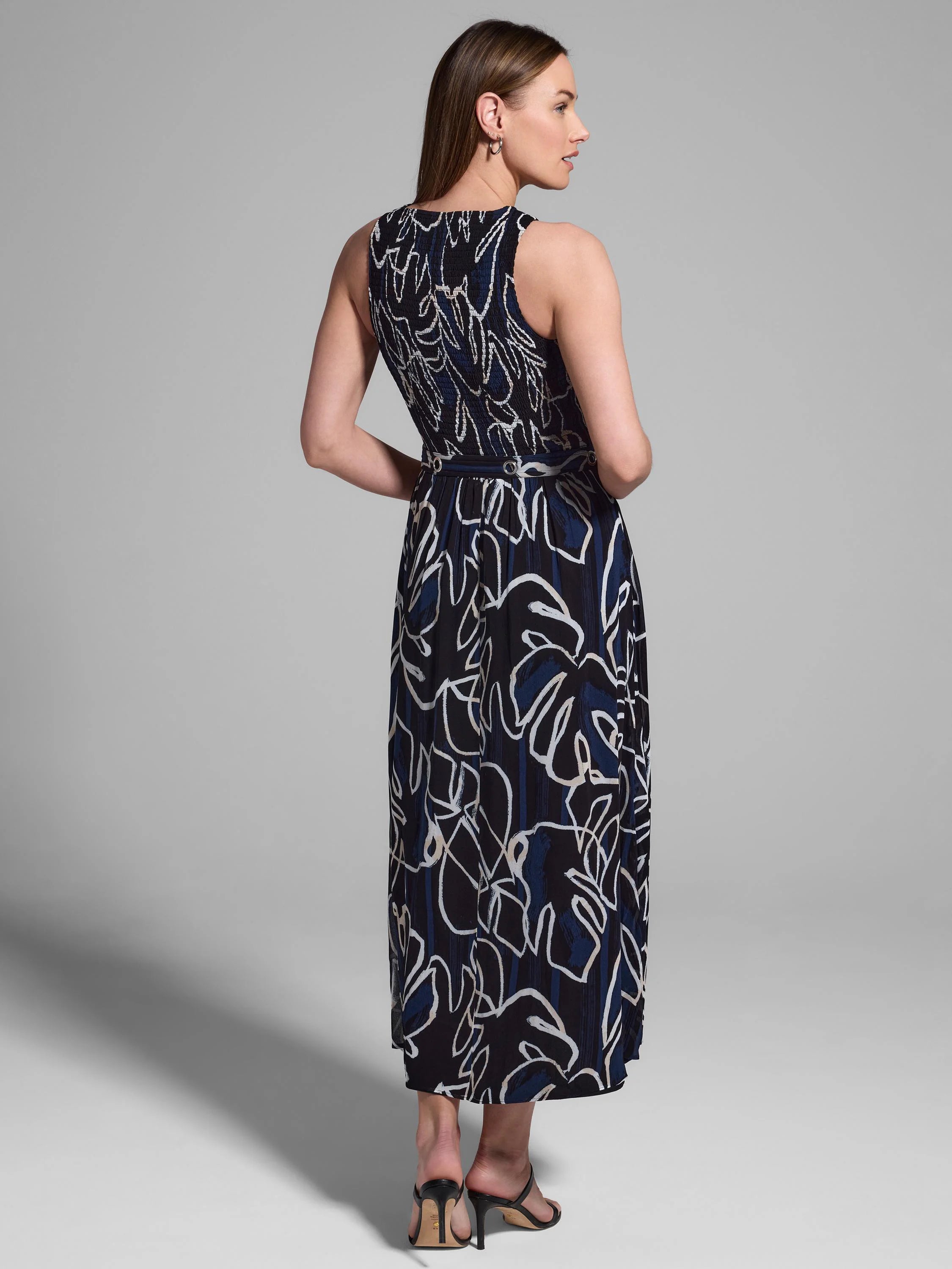 Midnight blue sleeveless midi dress with an abstract white and blue leaf print.  Back view.
