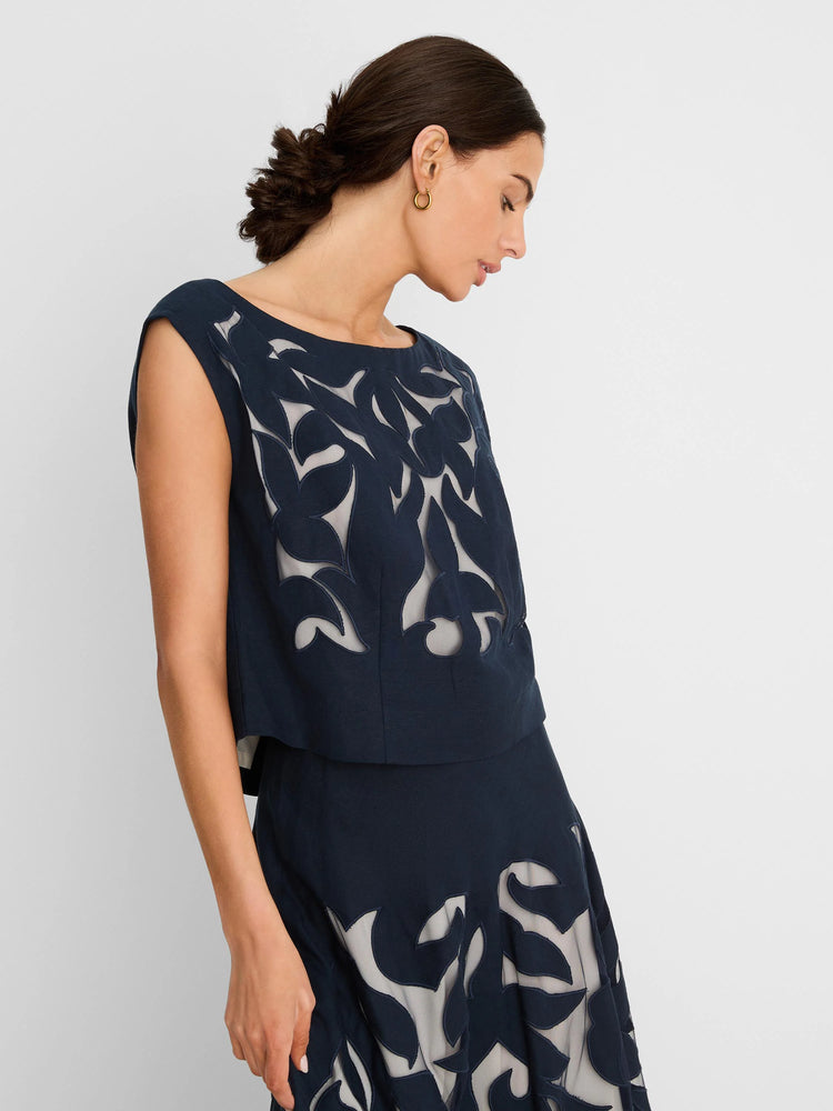 Navy linen cut out top with a leaf pattern revealing a sheer light underlay. Sleeveless, round neck.