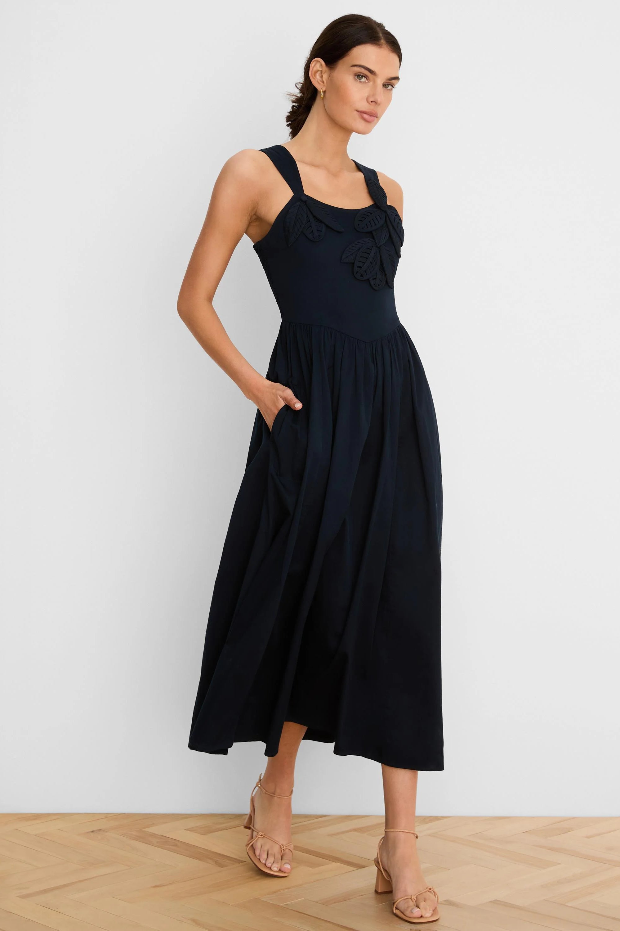 Navy midi dress with leaf appliques on bodice, sleeveless, v-waist, full skirt, and side pockets.