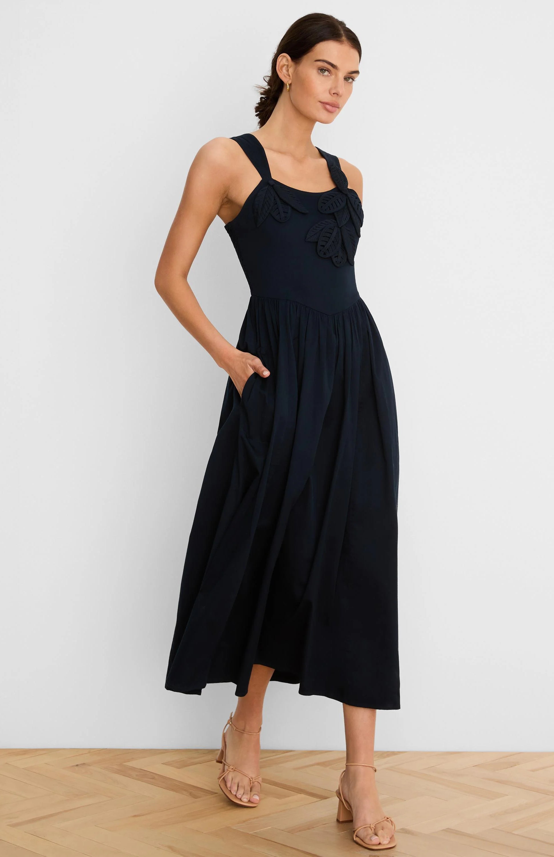 Navy midi dress with leaf appliques on bodice, sleeveless, v-waist, full skirt, and side pockets.