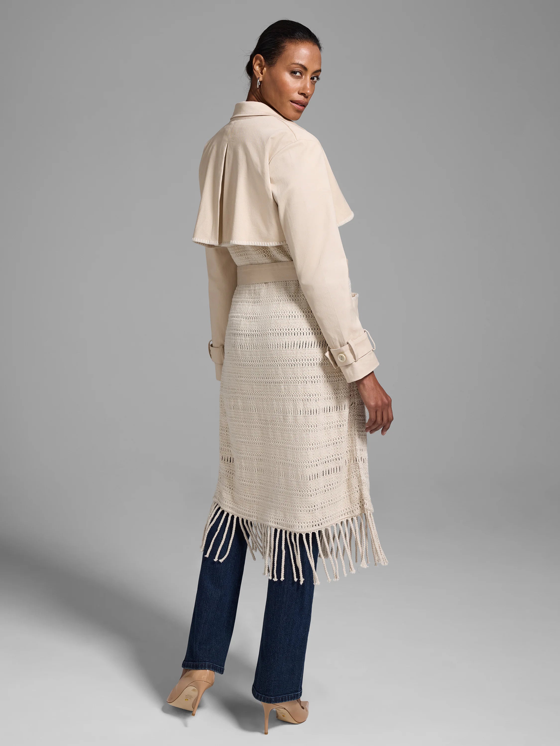 Beige trench coat with crocheted lower section and fringe.  Features a belted waist and pockets.