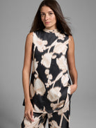 Black sleeveless top with beige floral print.  High neck, A-line shape.