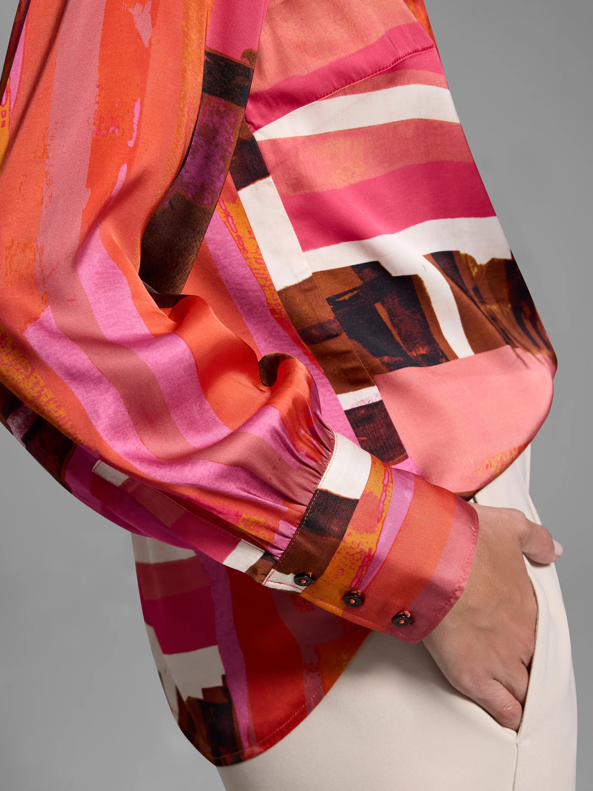 Glossy blouse with abstract horizontal stripes in pink, orange, brown, and white.  Long sleeves, button cuffs.