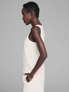 Cream sleeveless tank with smooth fabric shown on a model in profile.