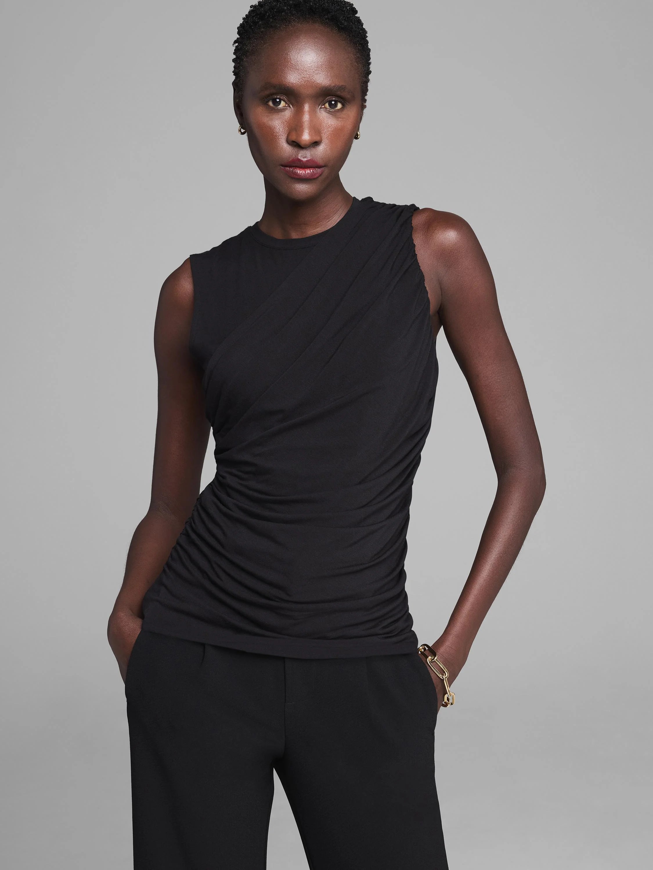 Black jersey tank with round neck and asymmetric diagonal drape across the chest, leading to gathered ruching.